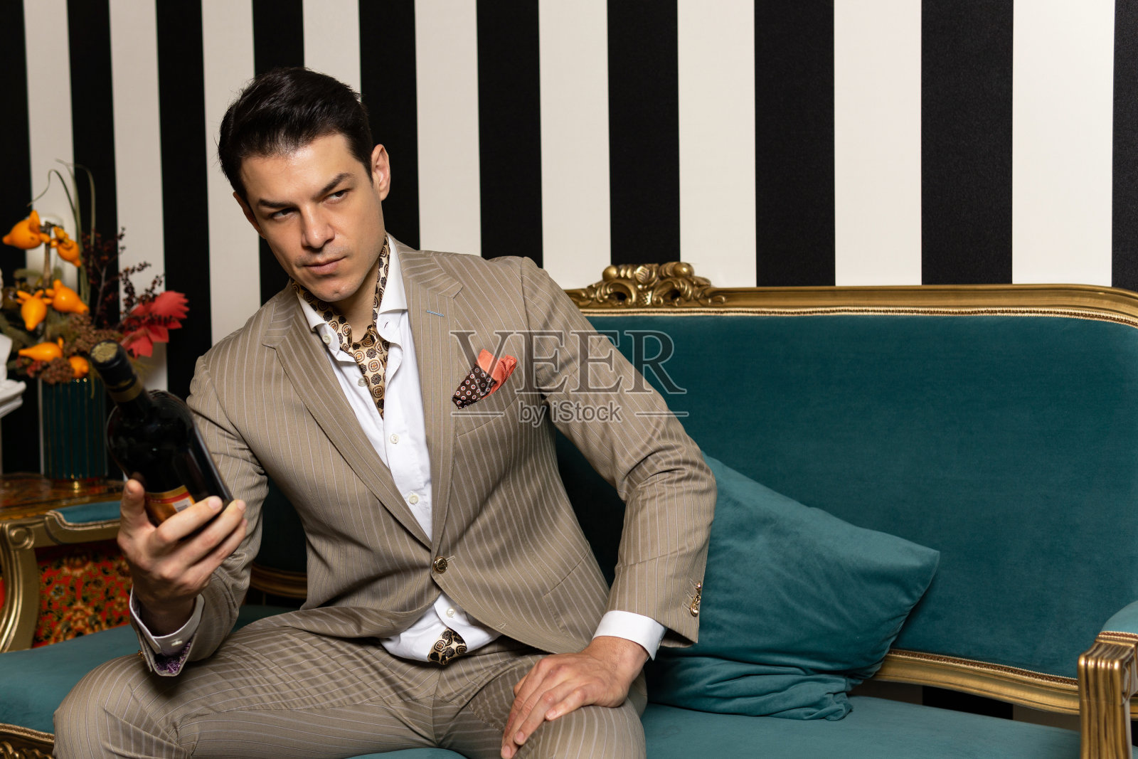 穿着西装拿着酒瓶的迷人男人。照片摄影图片