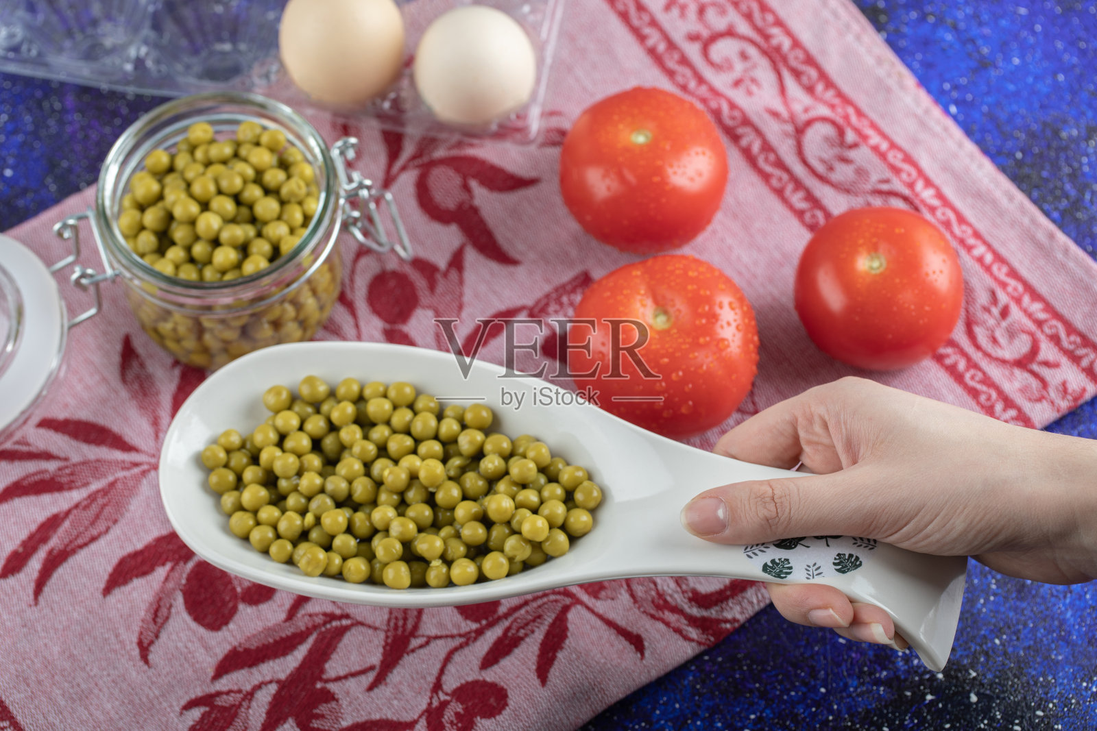 女人拿着一碗绿橄榄。背景是番茄和鸡蛋照片摄影图片