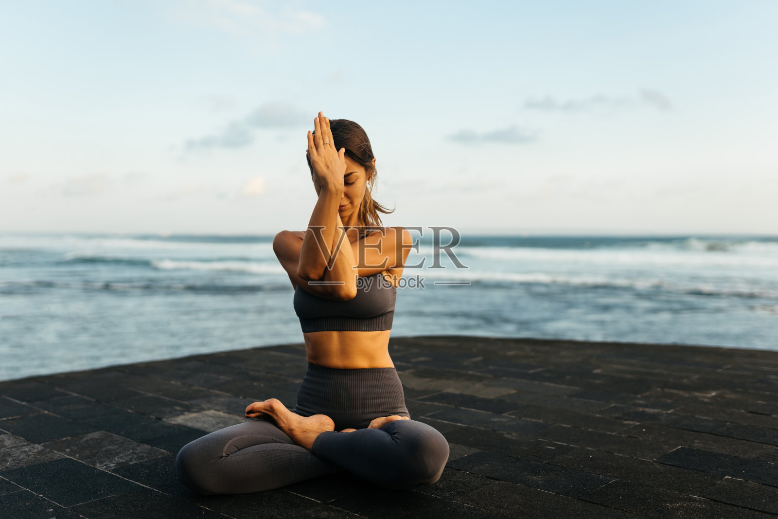 年轻美丽的女人在海滩上沉思。照片摄影图片