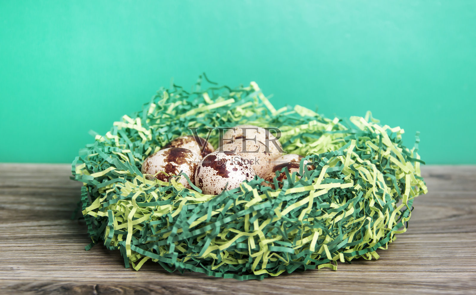 鹌鹑蛋放在一张木桌上的巢里。照片摄影图片