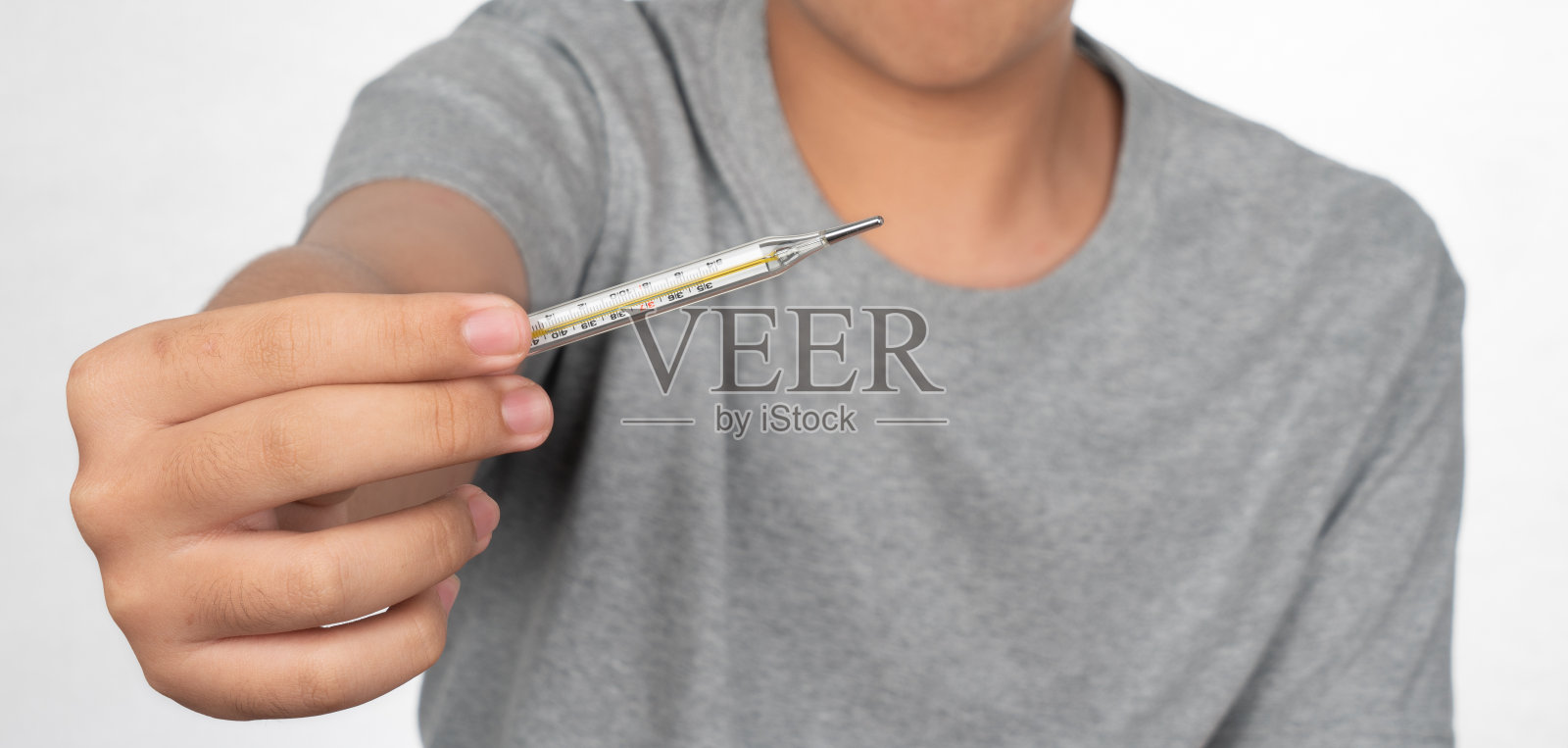 十几岁的男孩拿着数字体温计测量体温隔离在白色背景。带着水银数字温度计的男孩。照片摄影图片