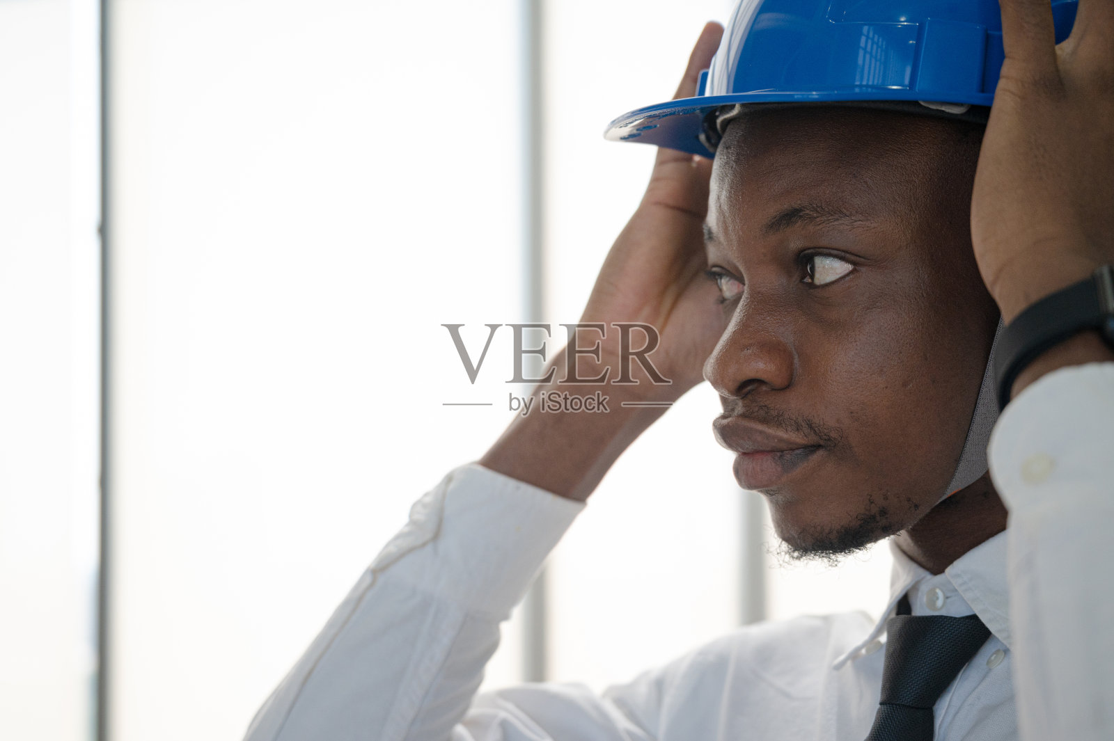 非裔美国工程师戴着头盔和正装白衬衫在办公室的肖像。照片摄影图片