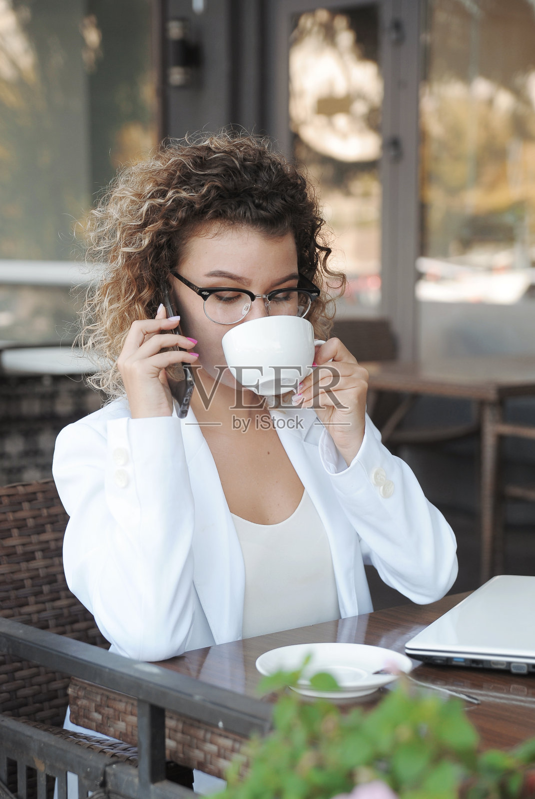 美女在咖啡馆喝咖啡。在户外使用笔记本电脑进行远程工作。照片摄影图片