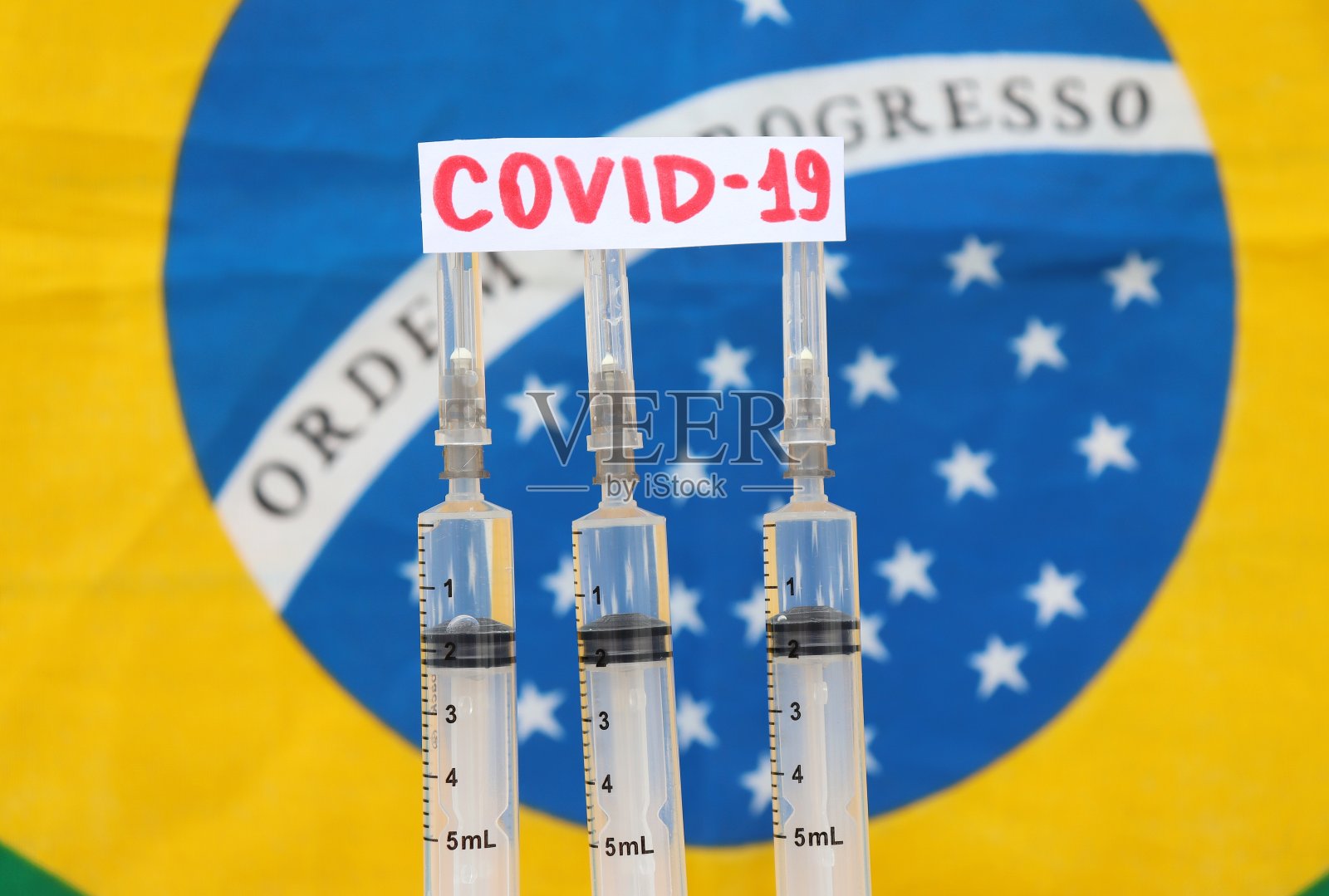 背景中印有Covid-19字样的注射器和巴西国旗。巴西的冠状病毒疫苗概念。照片摄影图片
