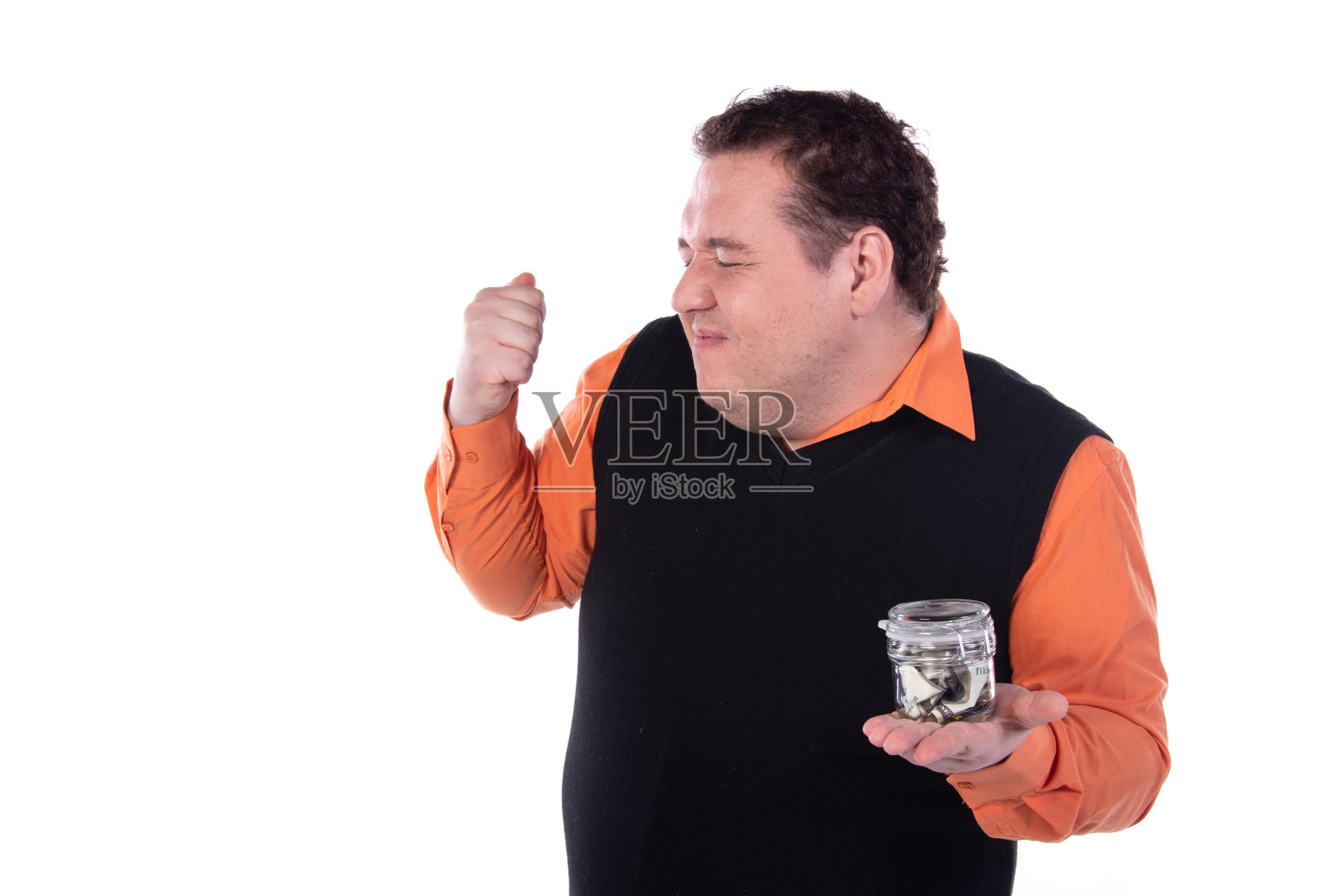 一个快乐的人正在一个玻璃罐子里存钱。照片摄影图片