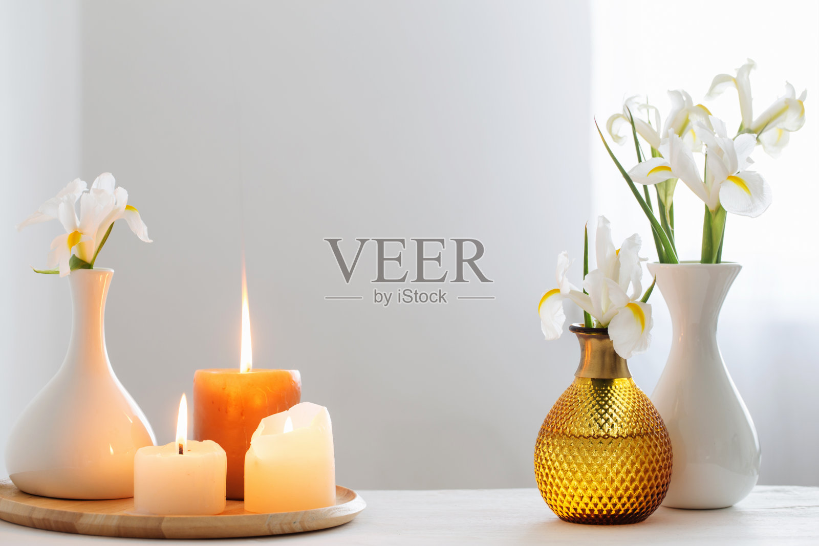 白色的室内木质架子上燃着蜡烛,盛开着春天的鲜花照片摄影图片