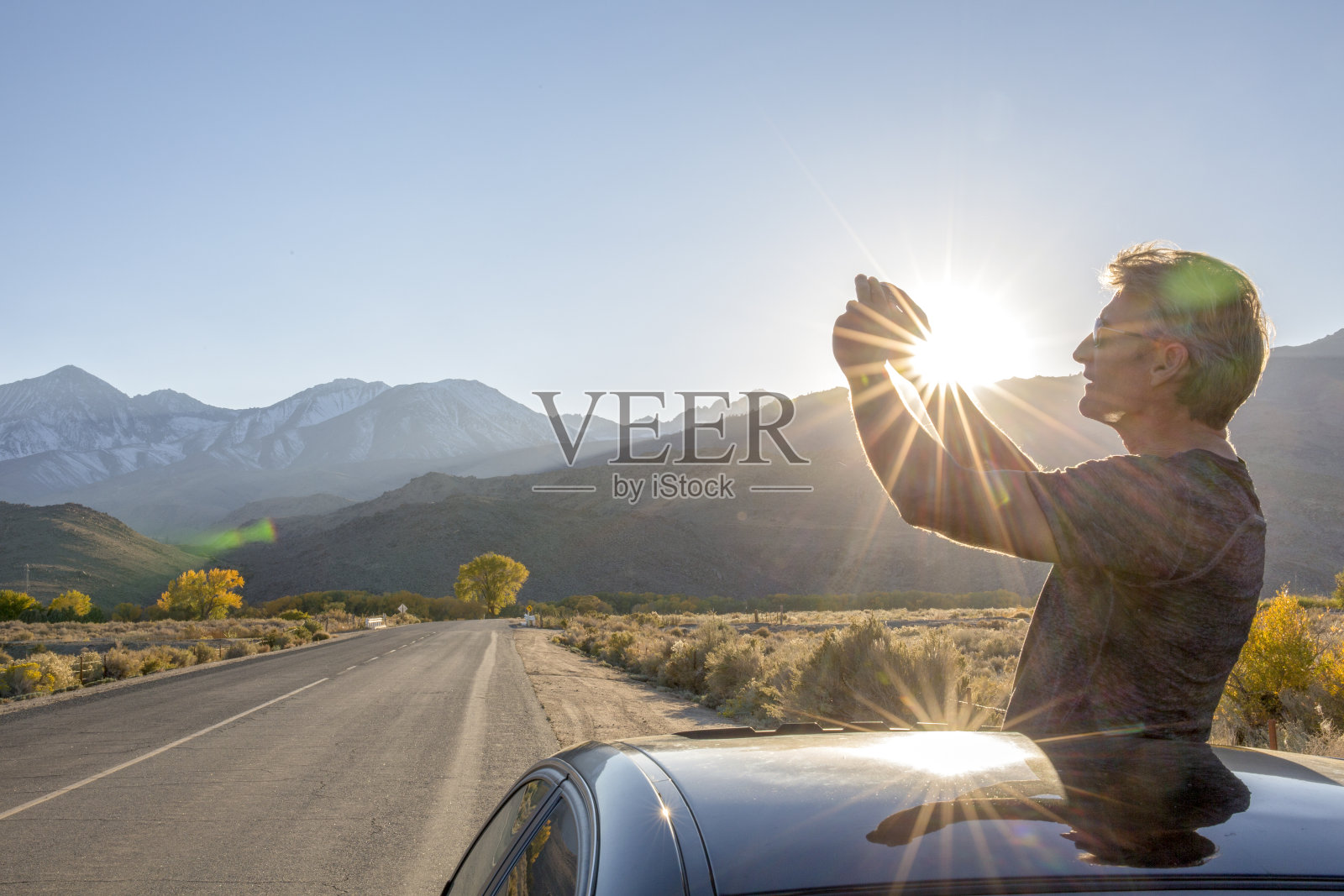 日落时分,一名男子在高速公路上用智能手机拍照照片摄影图片