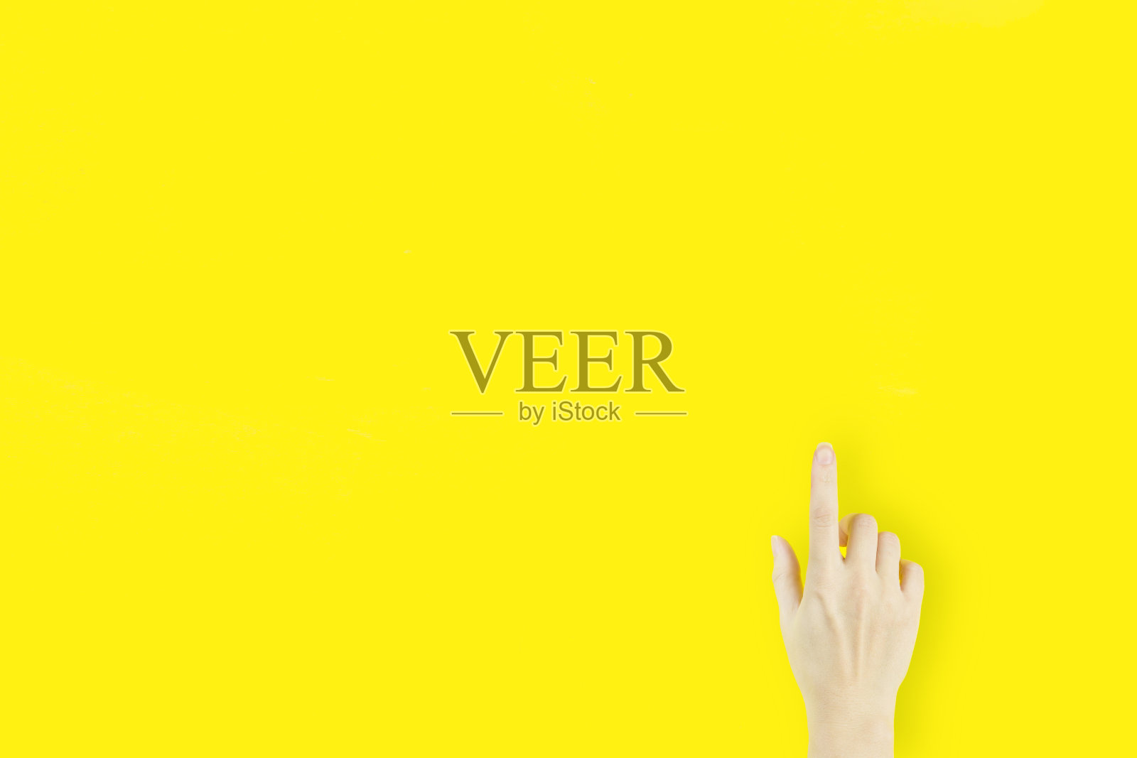 年轻女子的食指指向黄色背景上的手照片摄影图片