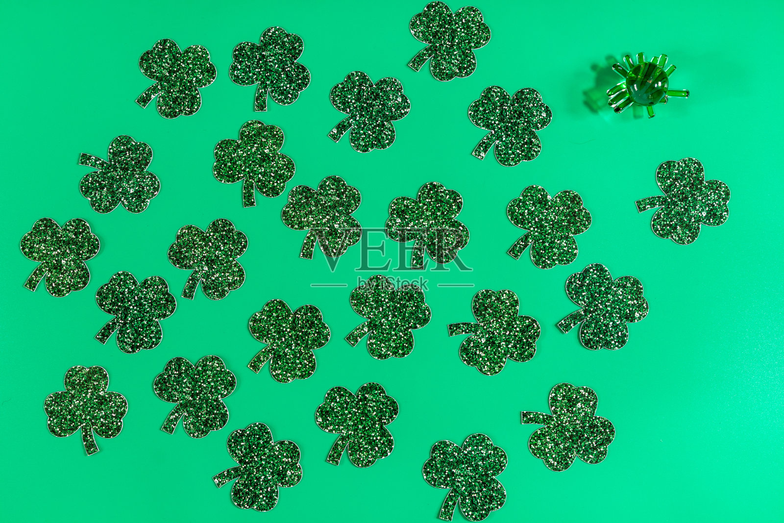 用三叶草叶子和绿色玻璃小雕像在绿色背景上的平铺构图照片摄影图片