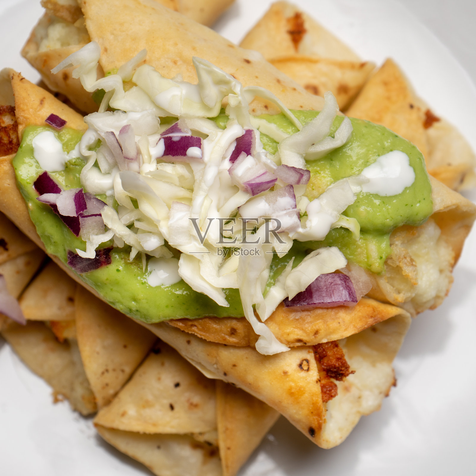 被称为弗拉塔斯的油炸玉米饼,配上鳄梨色拉酱和卷心菜在白色的背景上。墨西哥食物照片摄影图片