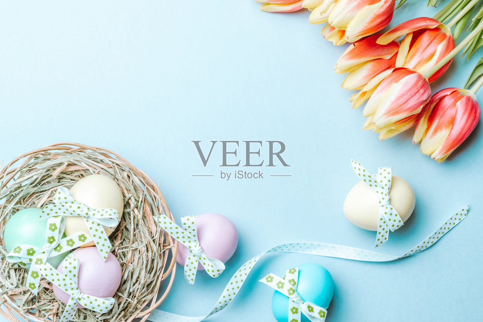 复活节黄金。彩色的彩蛋与丝带,春天的郁金香,羽毛在柔和的蓝色背景在快乐复活节装饰。传统的俯视图设计。照片摄影图片