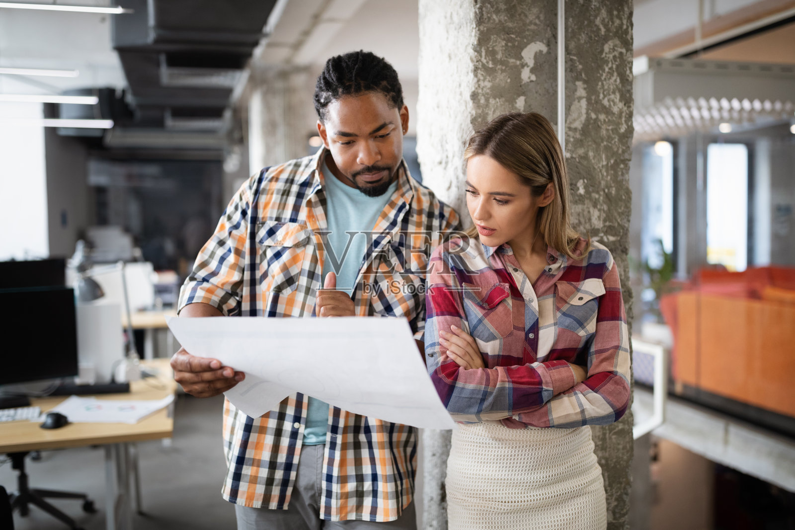 年轻的建筑师同事正在分析蓝图,同时工作在一个新的项目照片摄影图片