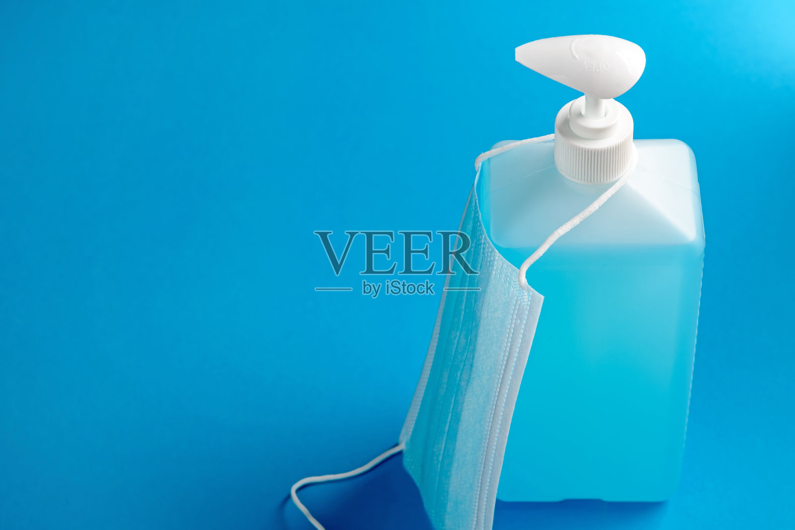 一瓶蓝色背景的消毒和医用口罩。医疗保健的概念。副本的空间。照片摄影图片