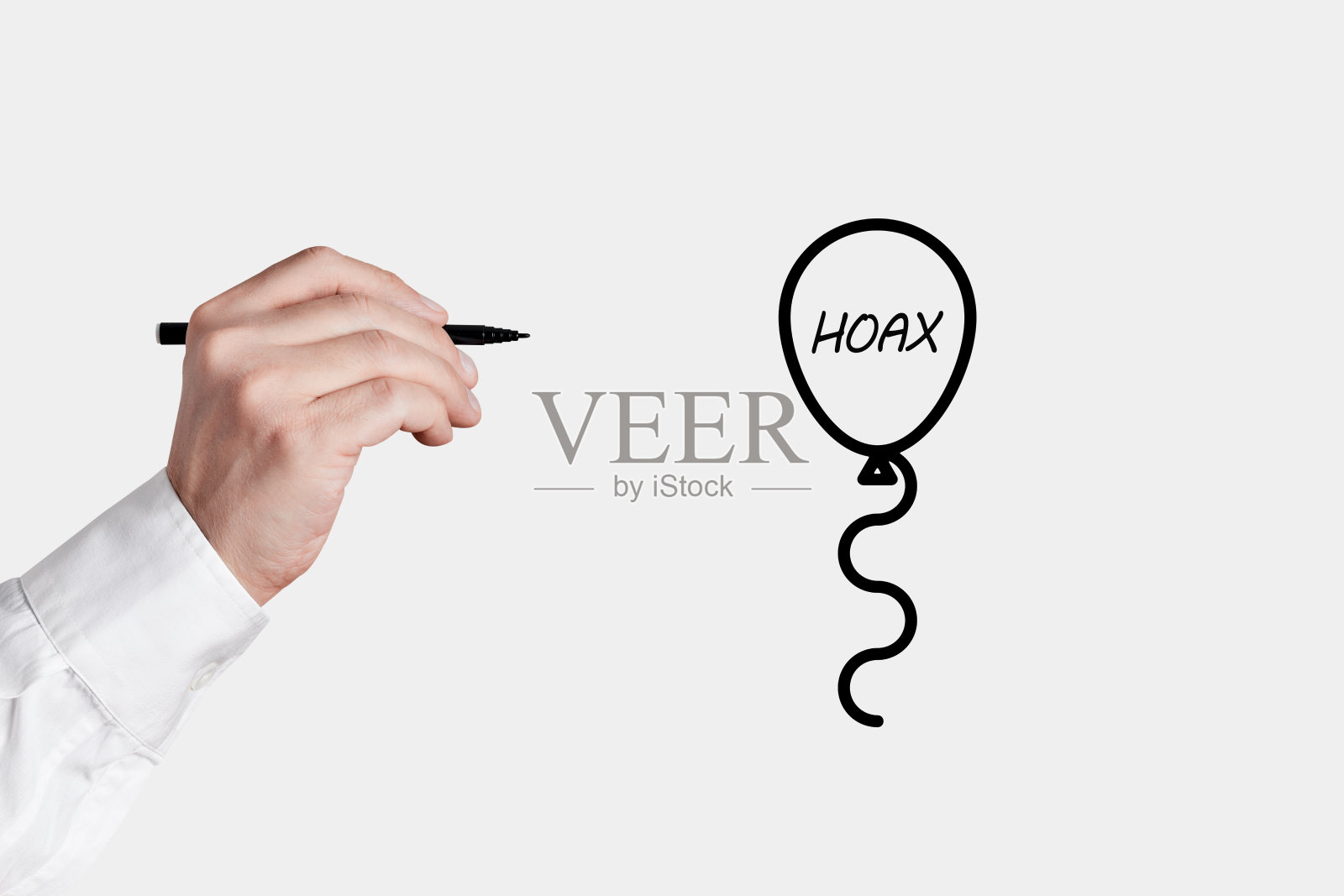 一个拿着笔的商人要用“恶作剧”这个词戳破一个气球图标。揭露事实真相照片摄影图片