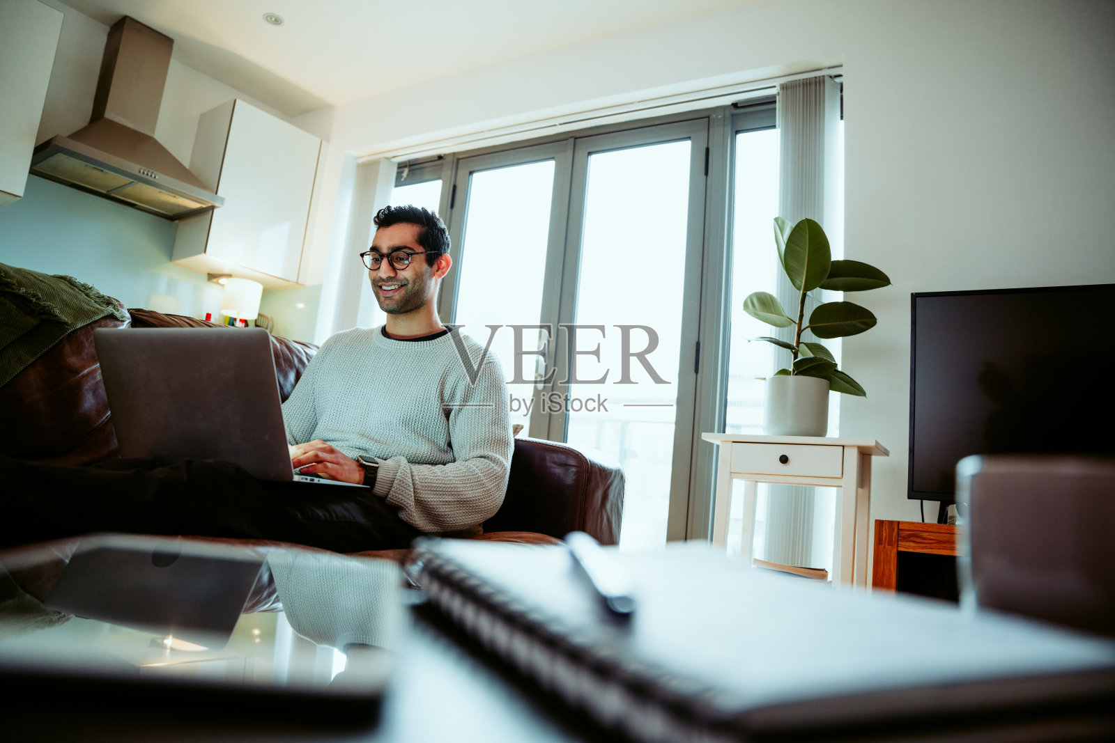 混血儿男学生在家工作,坐在舒适的沙发上用笔记本电脑打字,赶最后期限照片摄影图片
