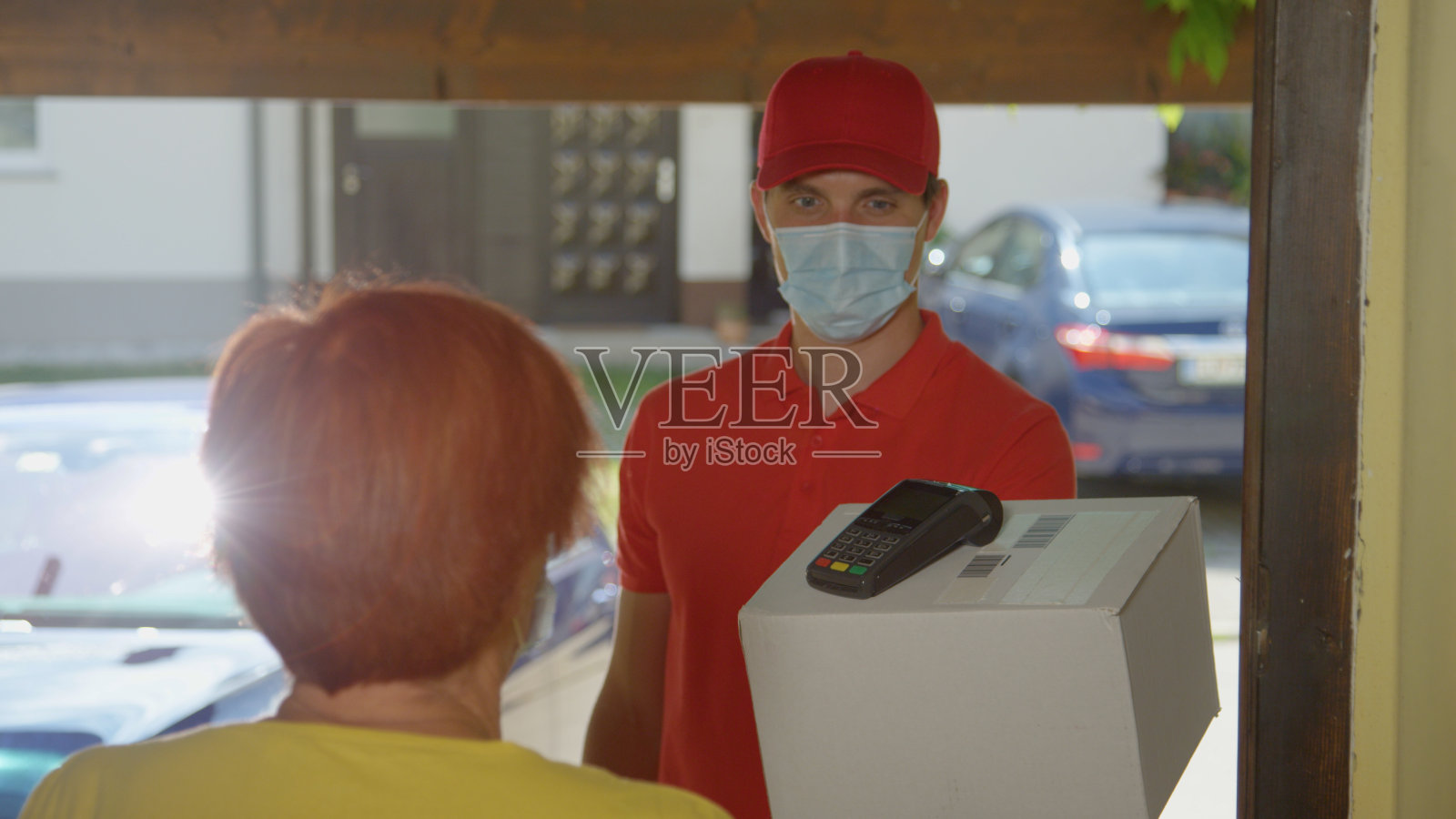 特写:一位老妇人用信用卡为这位礼貌的快递员的包裹买单。照片摄影图片
