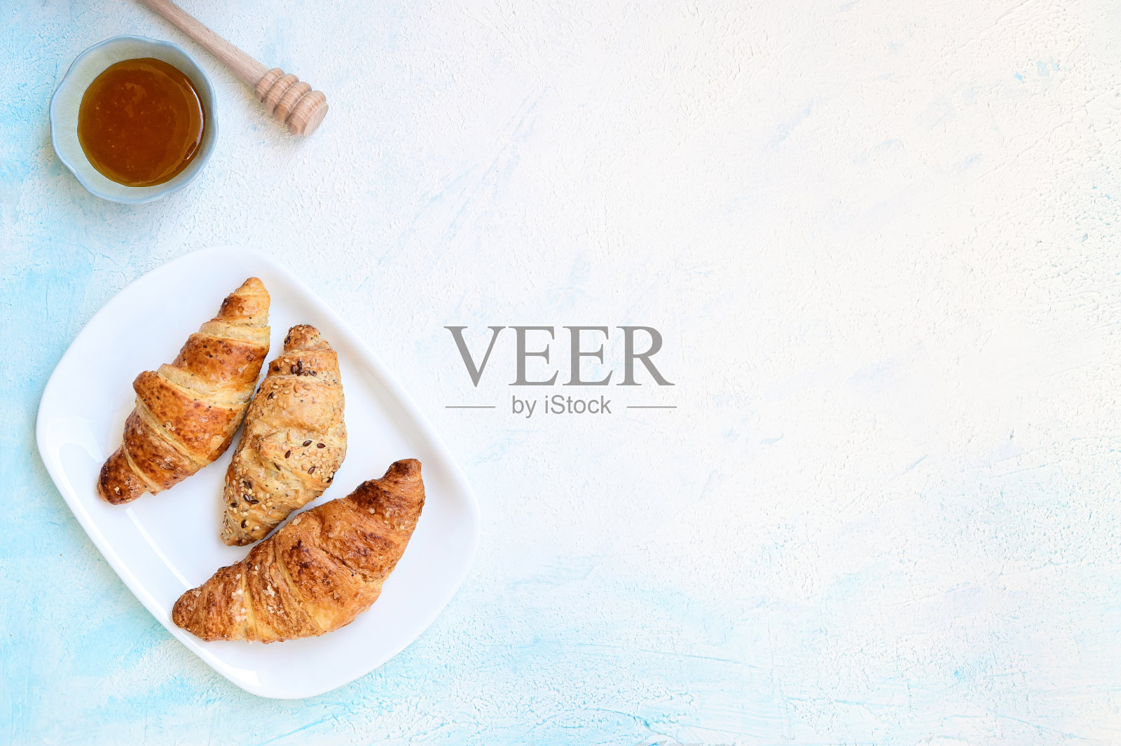 在白色的背景下用蜂蜜烤牛角面包照片摄影图片