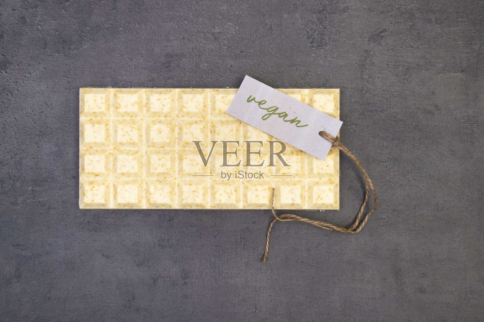 一块巧克力放在灰色的石头背景上,标签上写着“素食”和一串“n”照片摄影图片