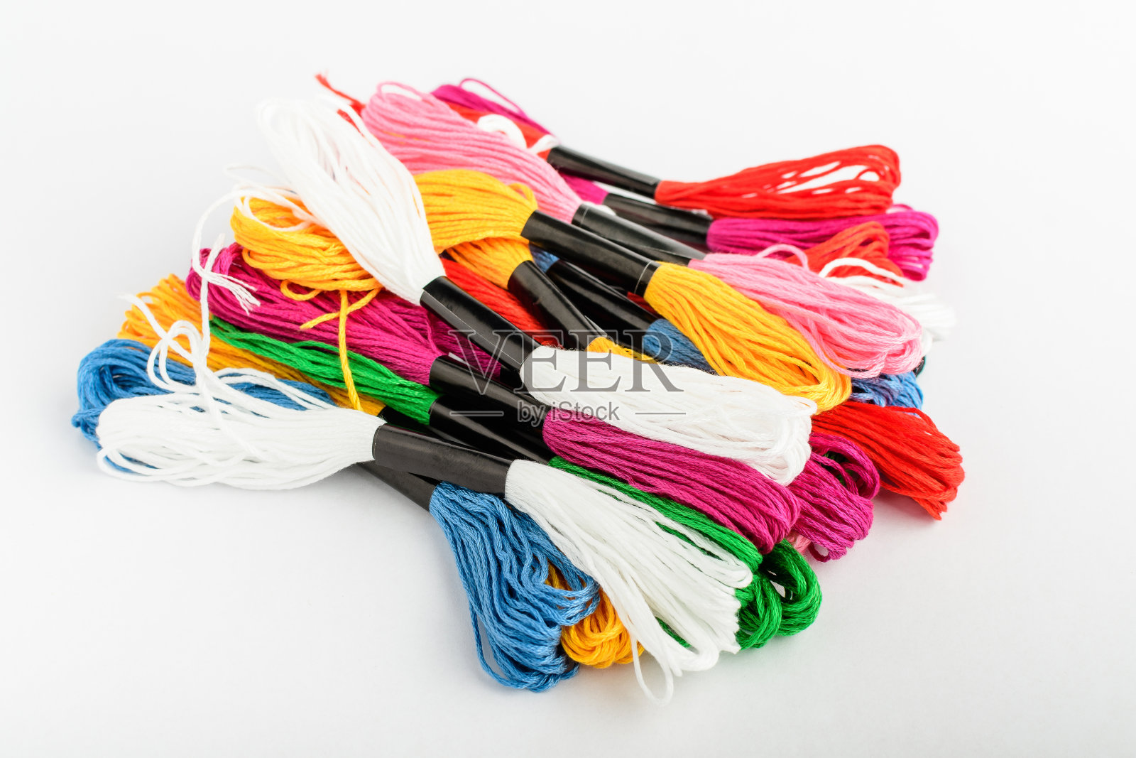 许多混合颜色鲜艳的刺绣缝纫线孤立在白色的桌子上,俯视图或平铺红色、粉色、黄色、蓝色和绿色的纺织材料照片摄影图片