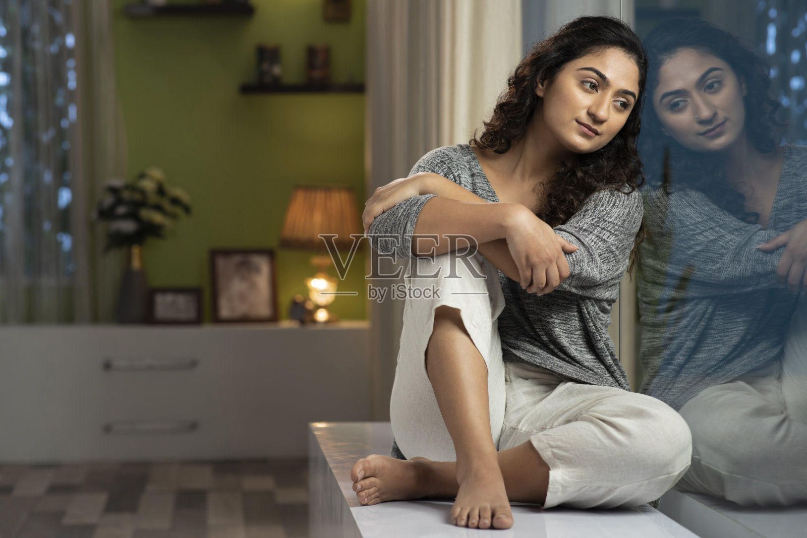 一个年轻女人坐在家里窗台上的照片,库存照片照片摄影图片