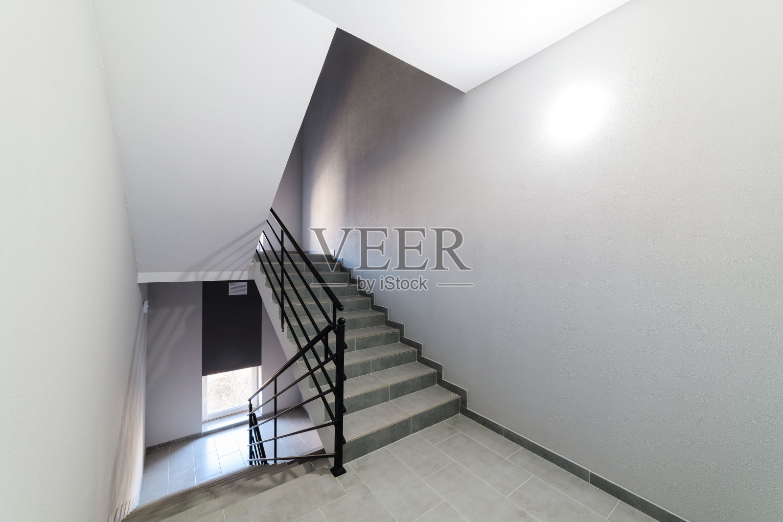 楼梯由瓷砖和金属黑色栏杆手工制作。照片摄影图片