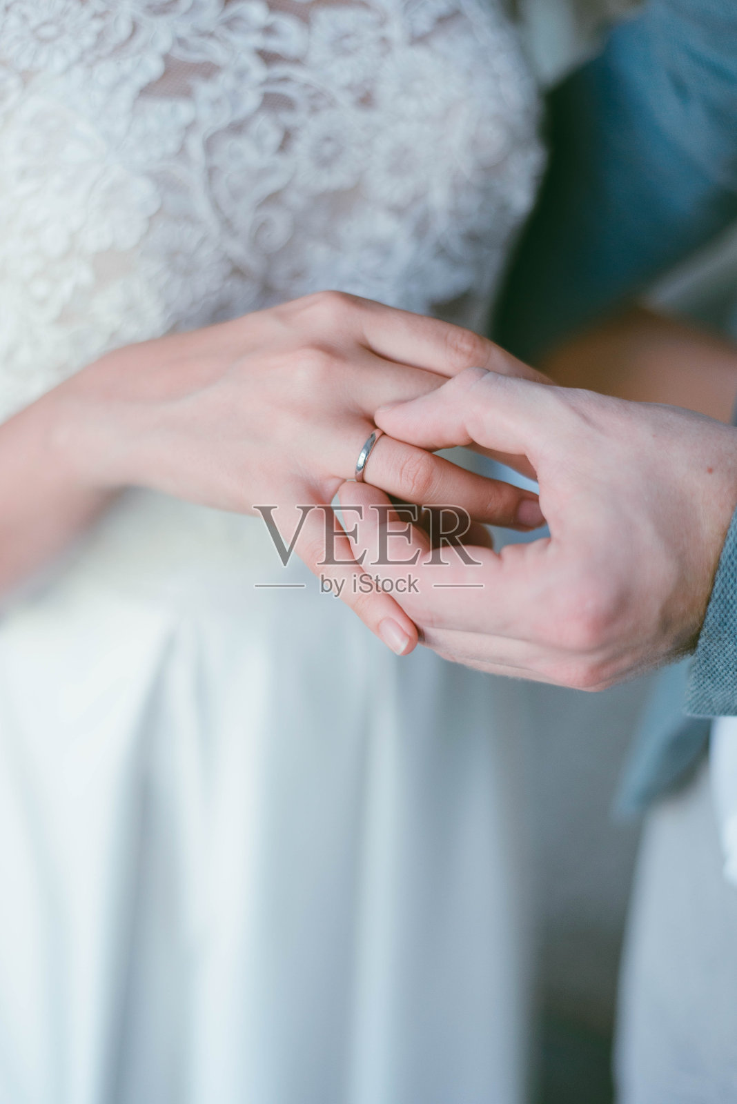 手指上戴着结婚戒指。新郎给新娘戴上戒指。婚礼照片摄影图片