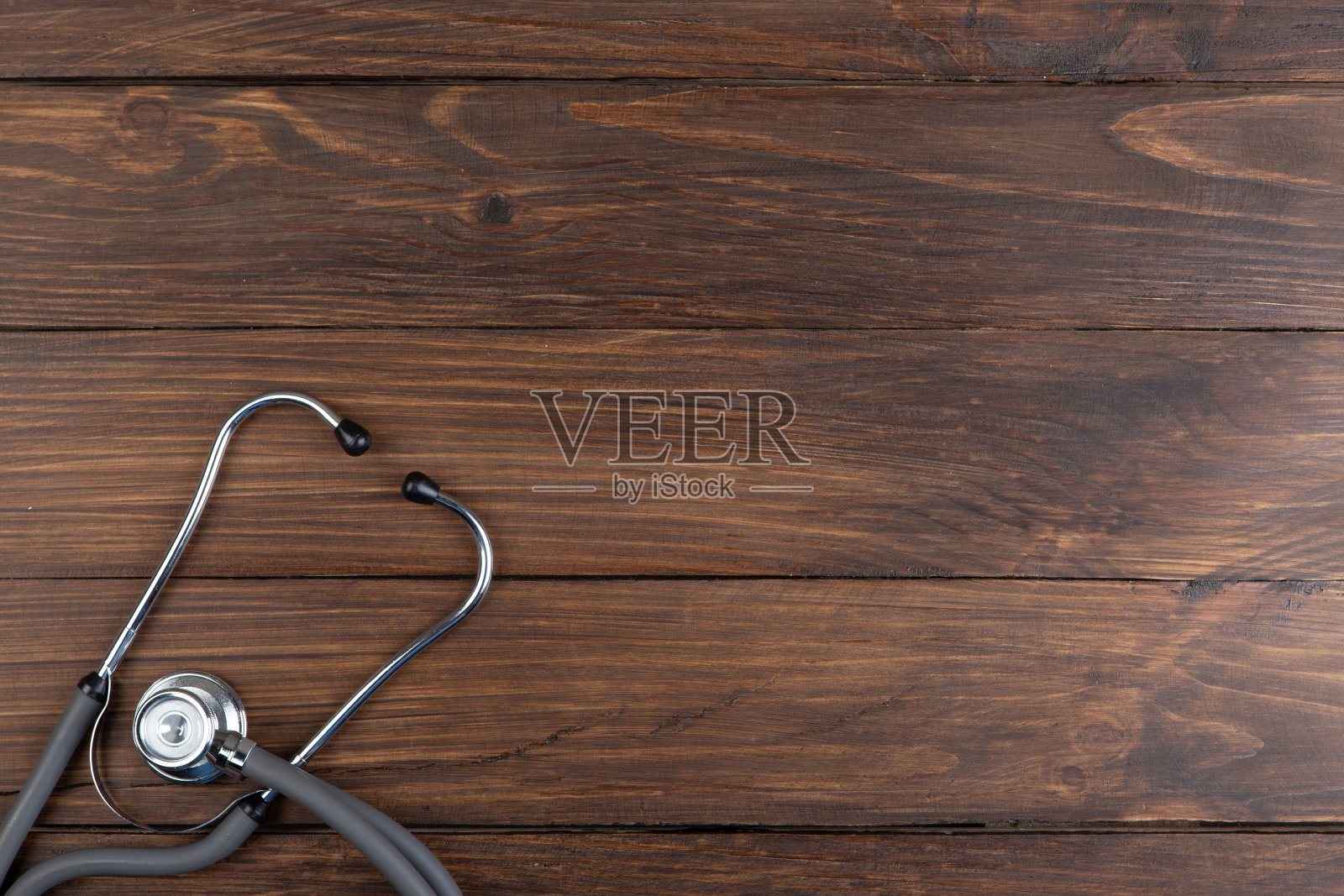医生的工作场所。听诊器和小心脏的木制书桌背景照片摄影图片