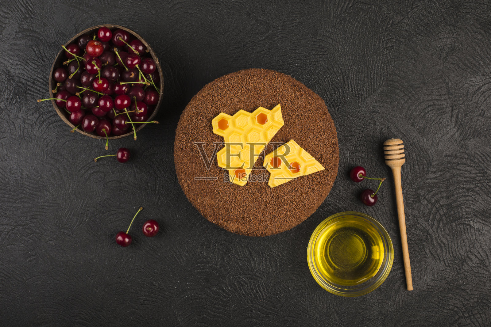 黑色背景上有樱桃的蜂蜜蛋糕。带有文本拷贝空间的顶视图。照片摄影图片