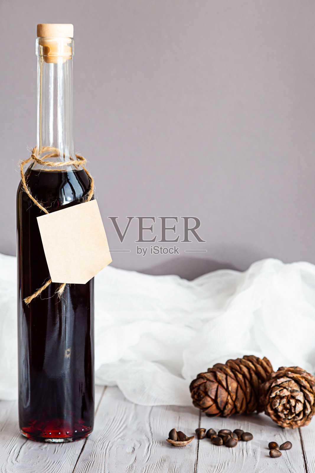 一瓶含有雪松果和松果的酒精酊。自制的有机酊剂,用于维生素缺乏症,关节炎,代谢紊乱。灰色背景下的现代静物画。照片摄影图片