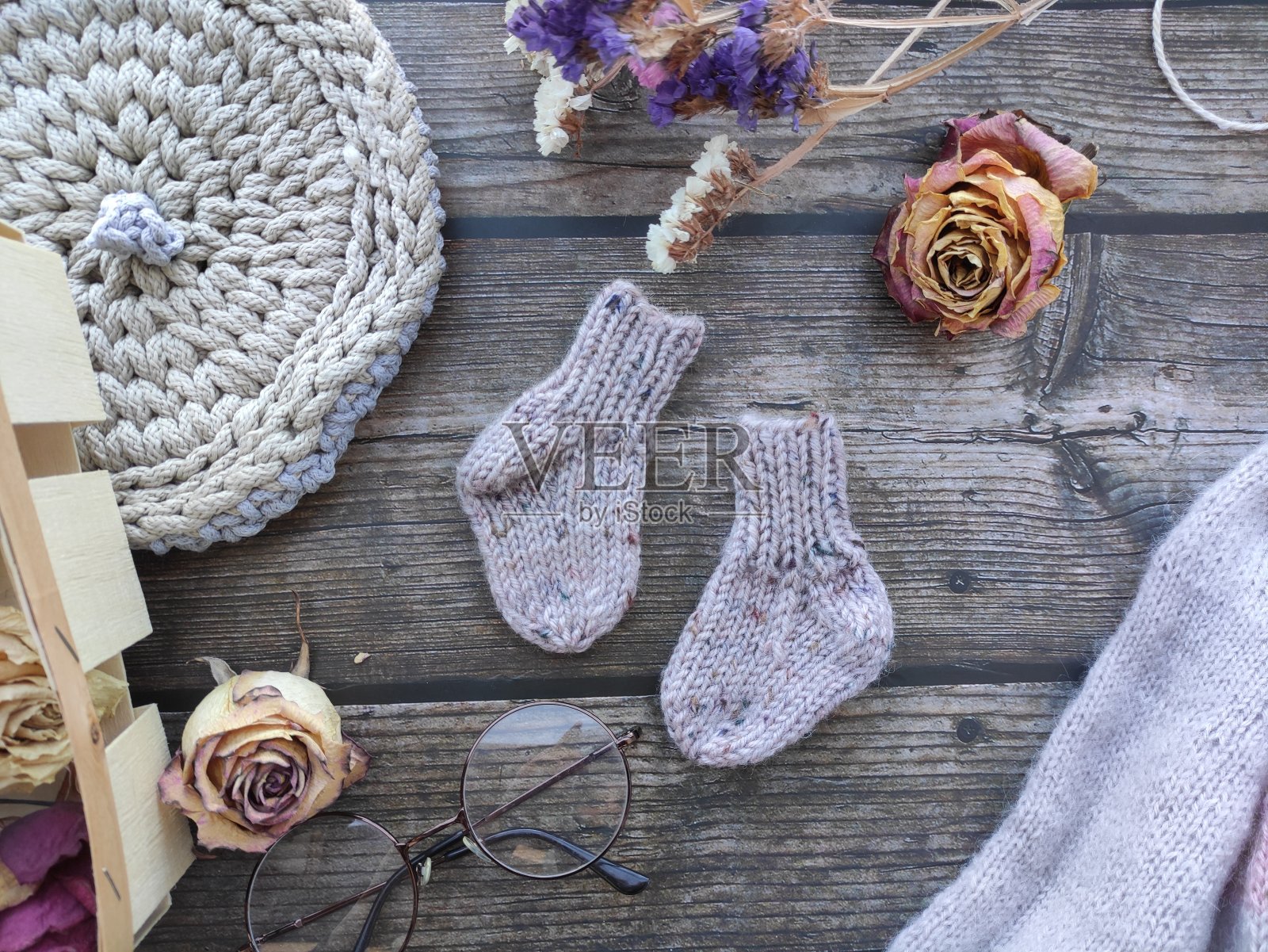 厚实可爱的新生袜子在深色的木制背景,复古的场景,老花镜,干花照片摄影图片