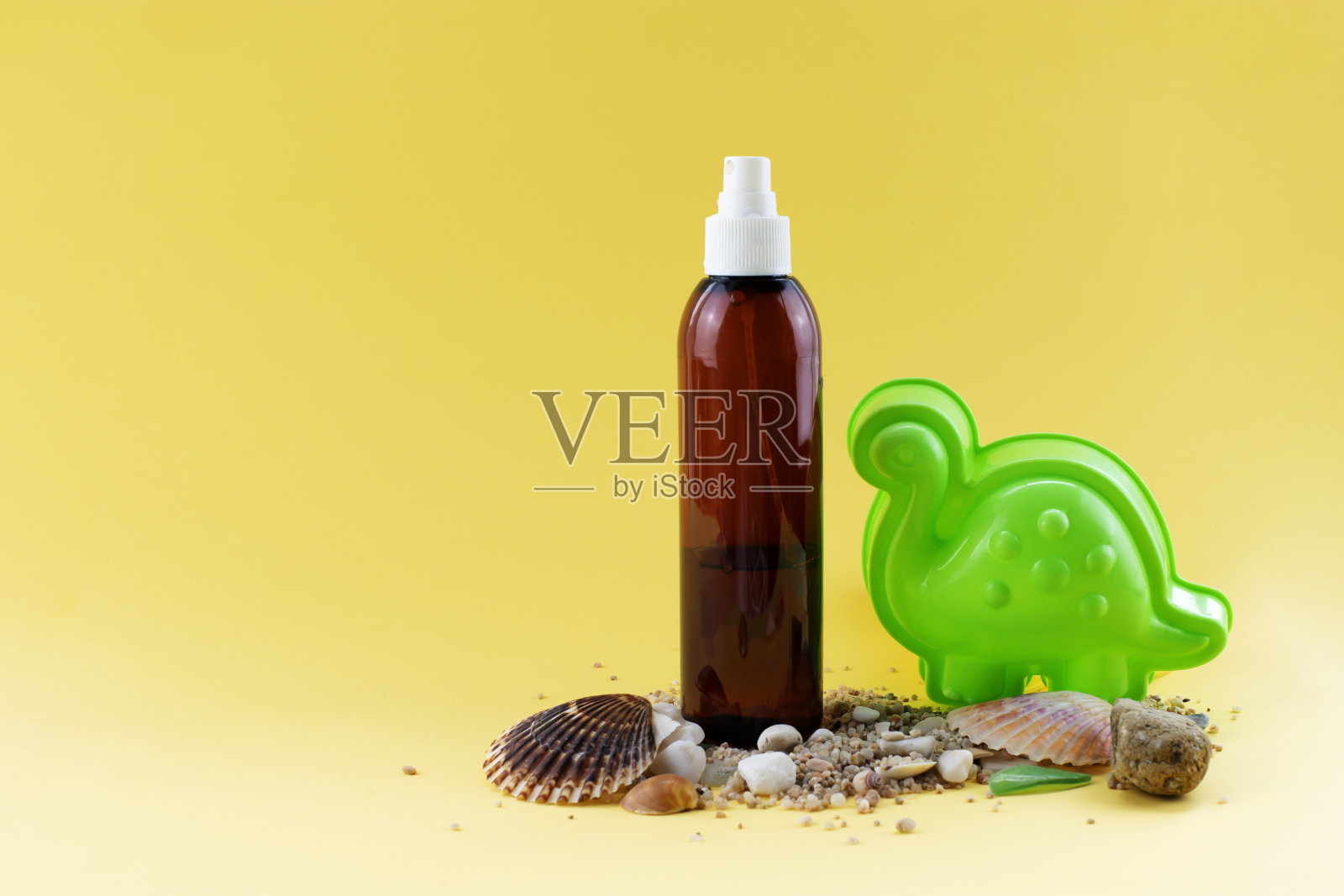 在沙滩上放一瓶防晒油,还有贝壳和海玻璃。照片摄影图片
