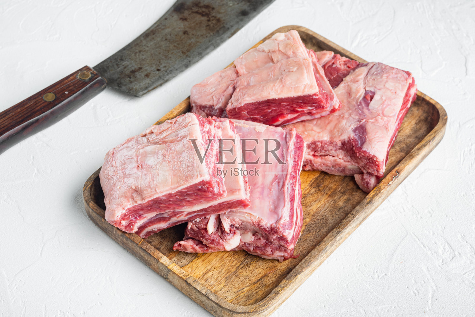 生牛肉短肋,和老屠夫切肉刀,在白石背景上照片摄影图片