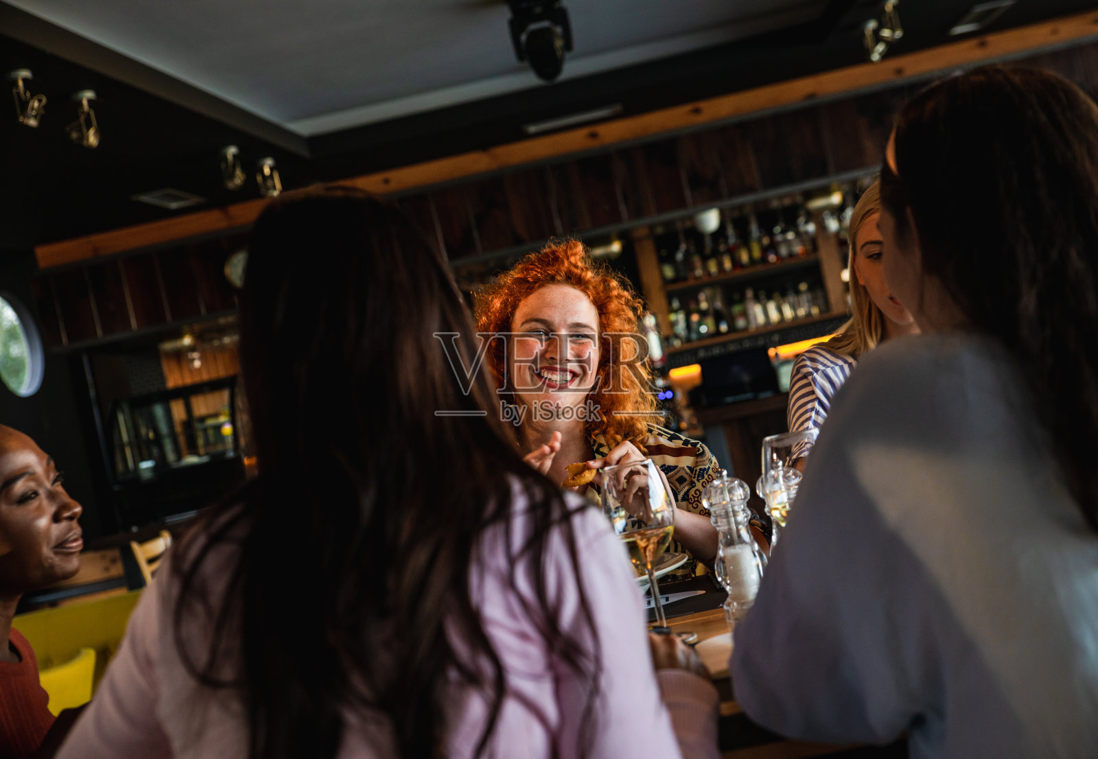 一群年轻的女性朋友在餐馆里玩乐,在餐桌上有说有笑。照片摄影图片