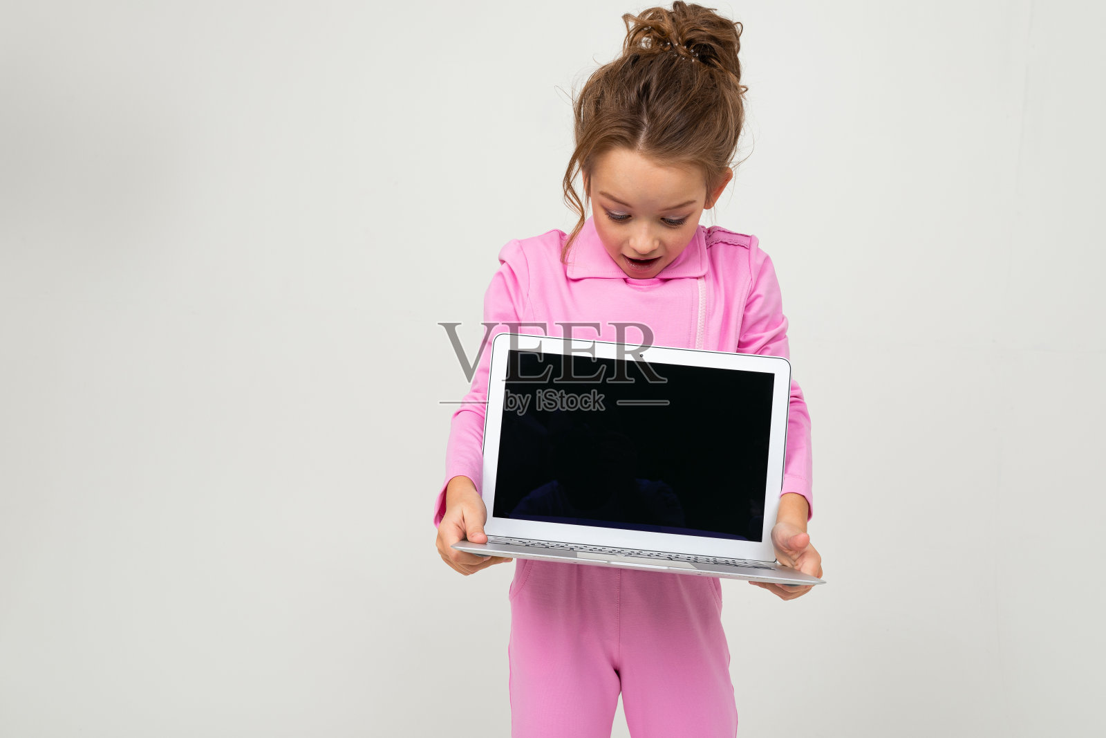 特写有吸引力的有趣迷人的婴儿在粉红色的服装显示笔记本电脑屏幕上模拟的白色背景照片摄影图片