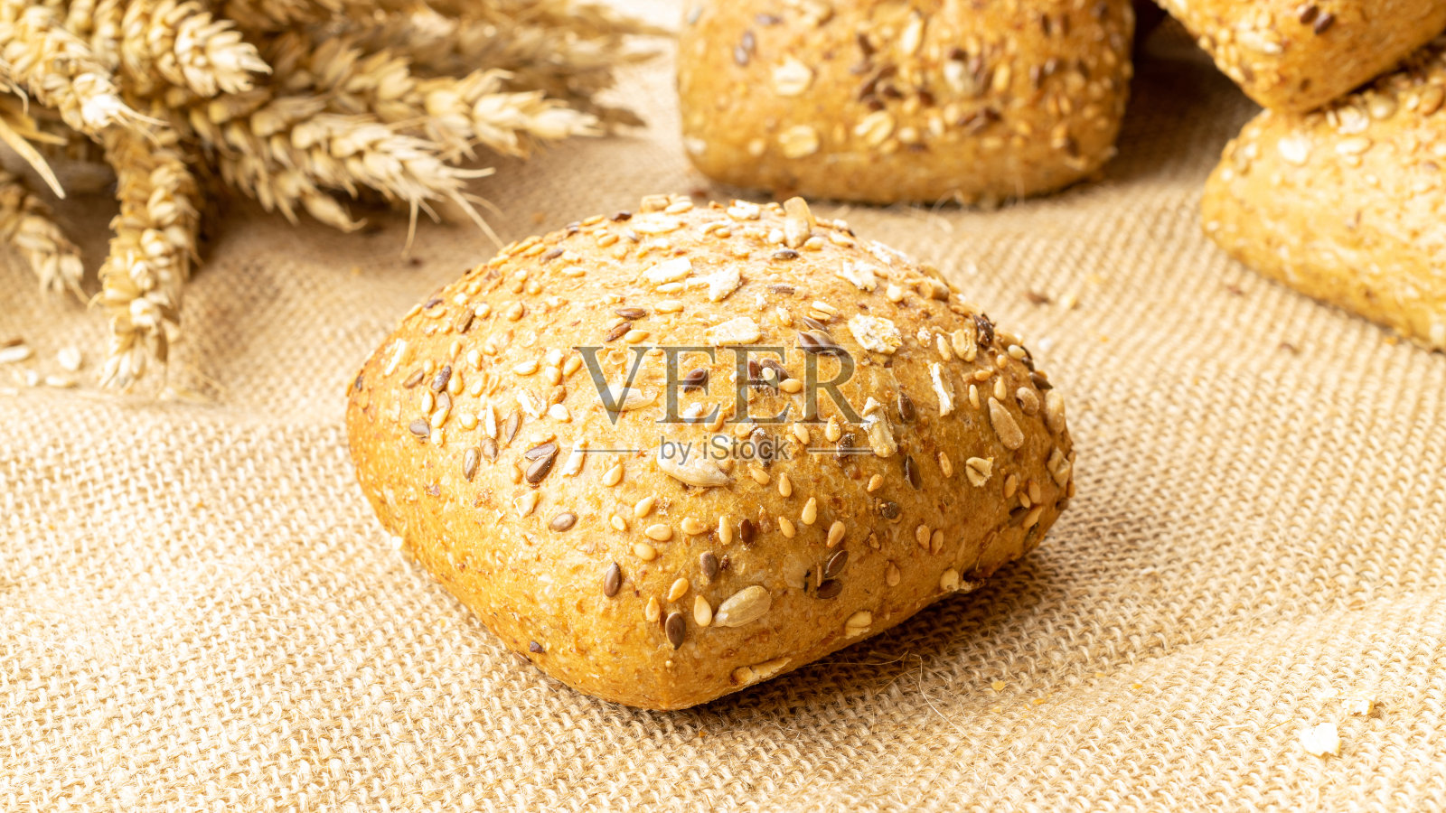 乡村黑麦。在亚麻质地的背景下,以小麦穗或穗状花序种植的乡村传统面包的新鲜面包。有硬面包和面包屑的面包房。烘焙产品标签的设计元素。照片摄影图片