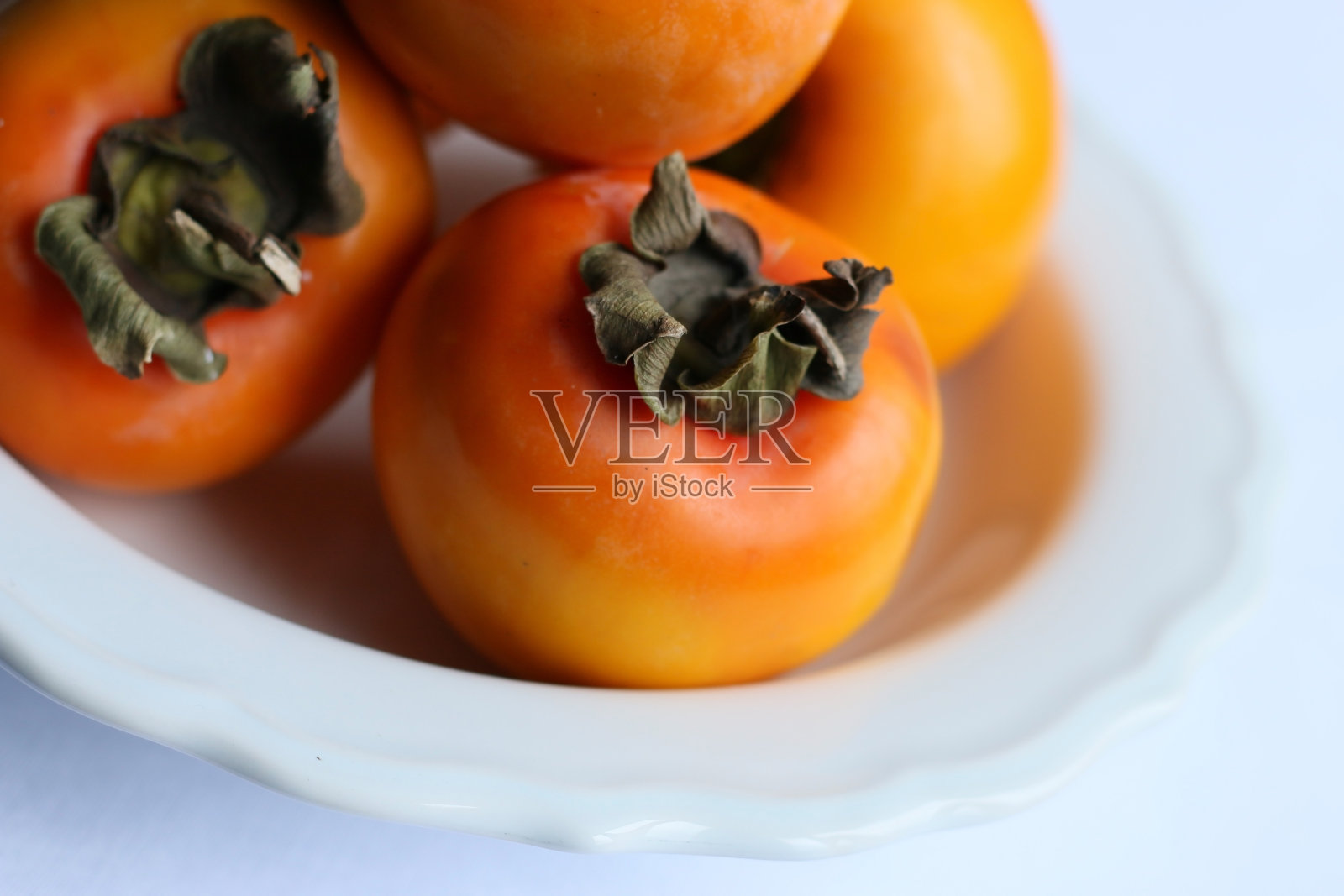 新鲜成熟的柿子在白色经典设计盘子,天堂棕榈树照片摄影图片