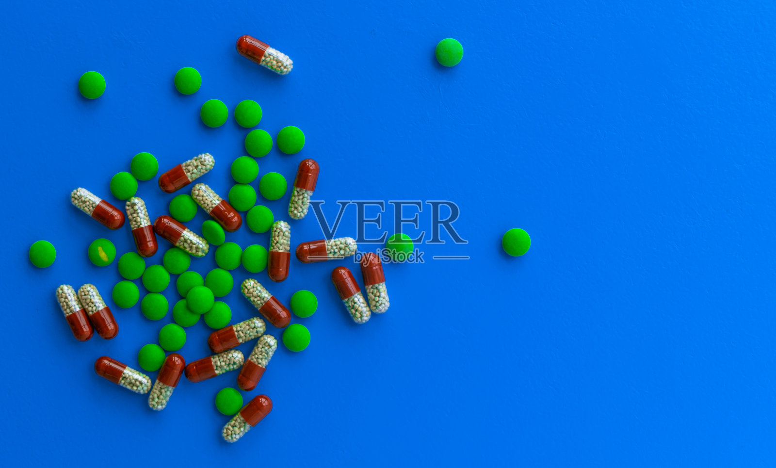 红色和白色胶囊和绿色药片在蓝色背景俯视图,药物,维生素照片摄影图片