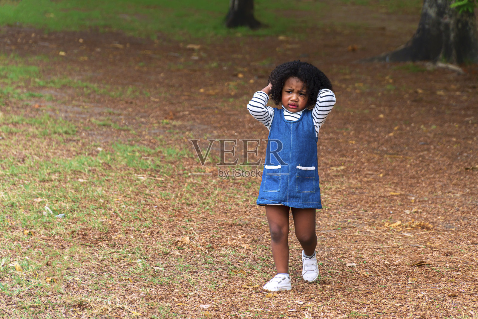 不开心的小可爱混着种族有一头不满意的卷发,在夏天漫步在大自然中。孤独天真的孩子在公园里看起来很担心。照片摄影图片