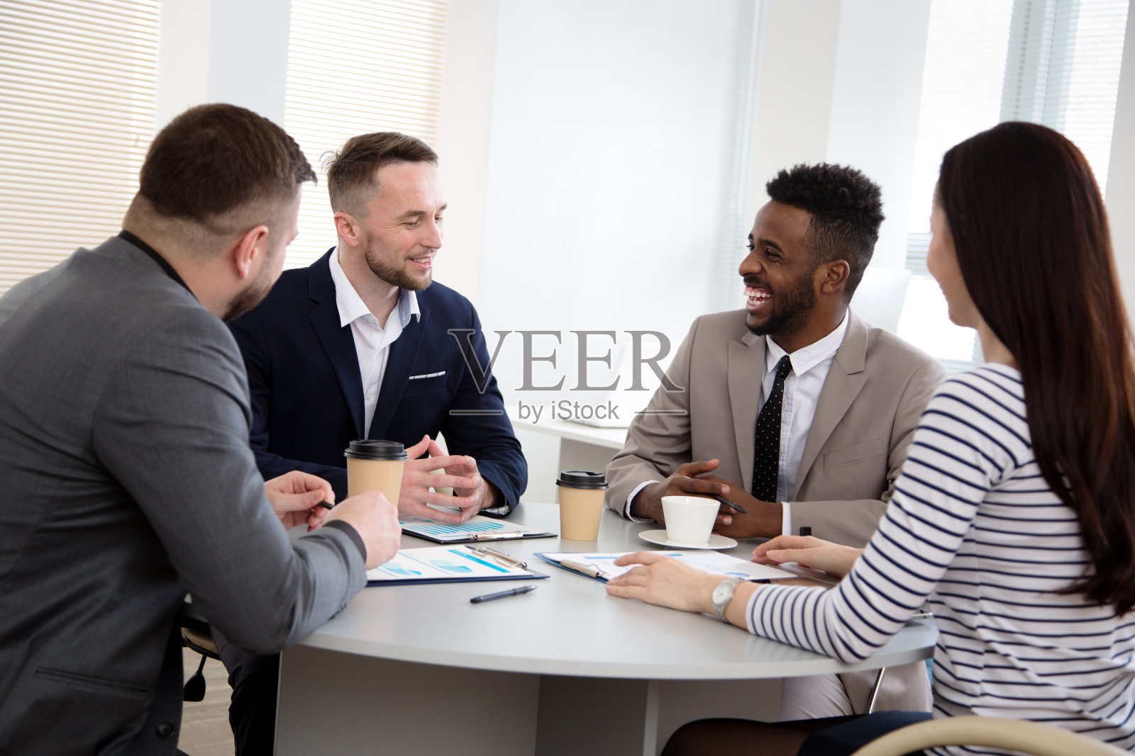 一群商务人士围坐在办公桌旁讨论项目照片摄影图片