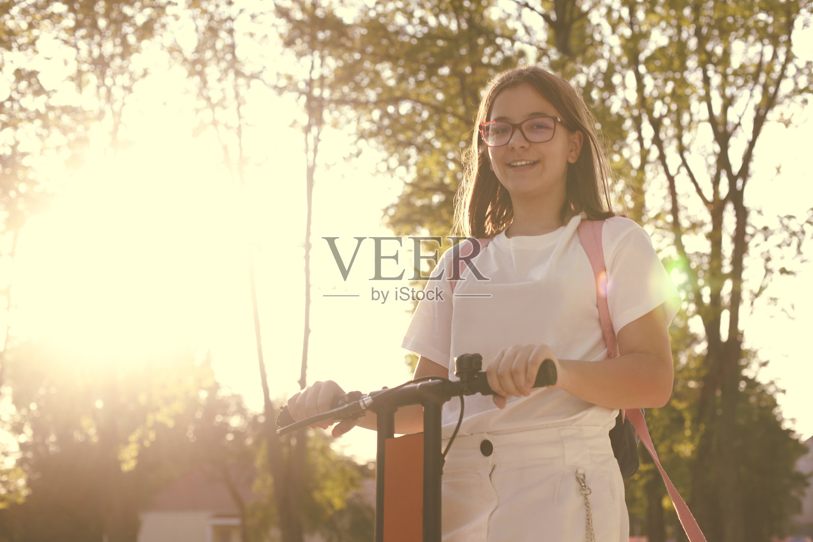 漂亮的年轻微笑的女学生骑蓝色电动滑板车照片摄影图片