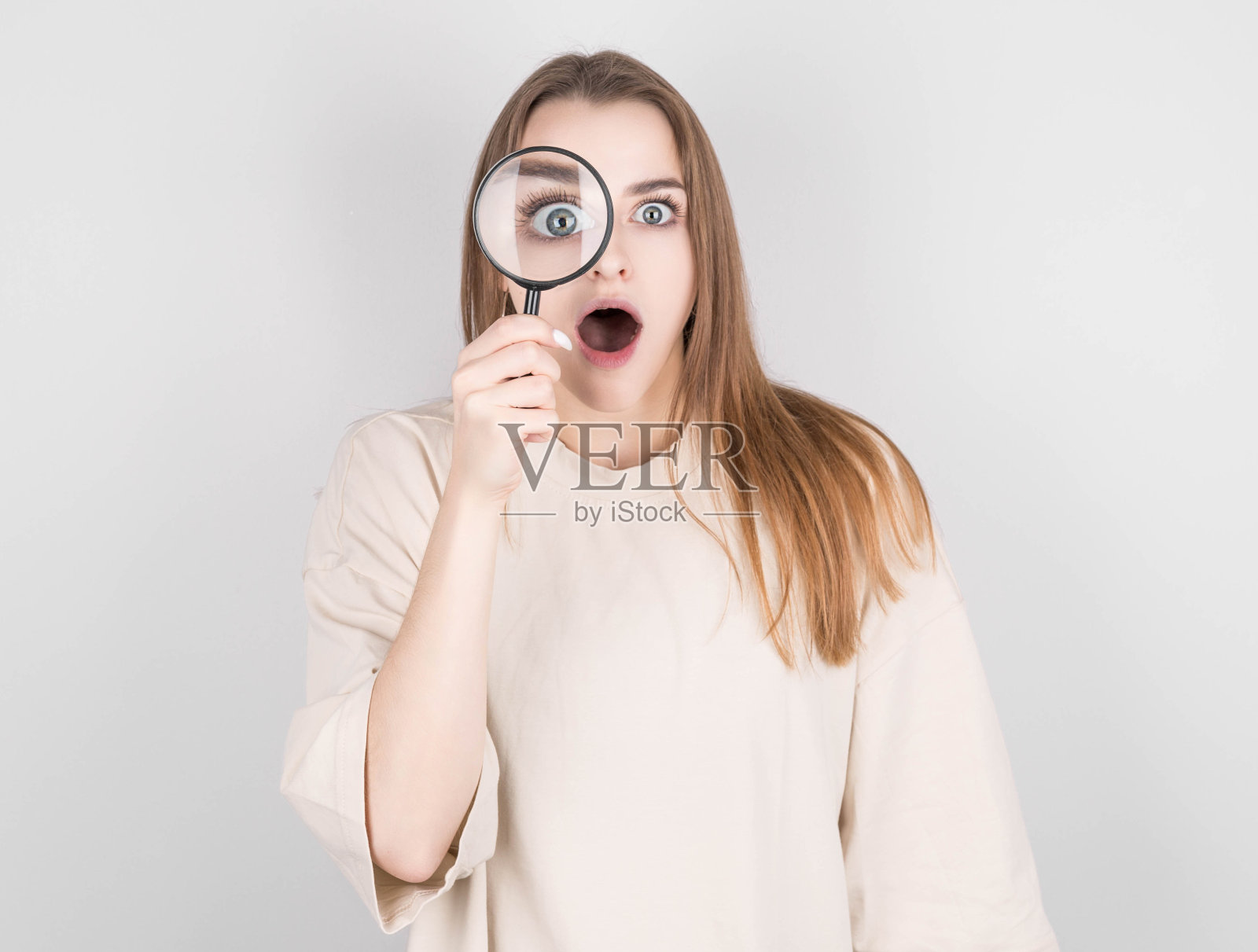 震惊的女人透过放大镜看照片摄影图片