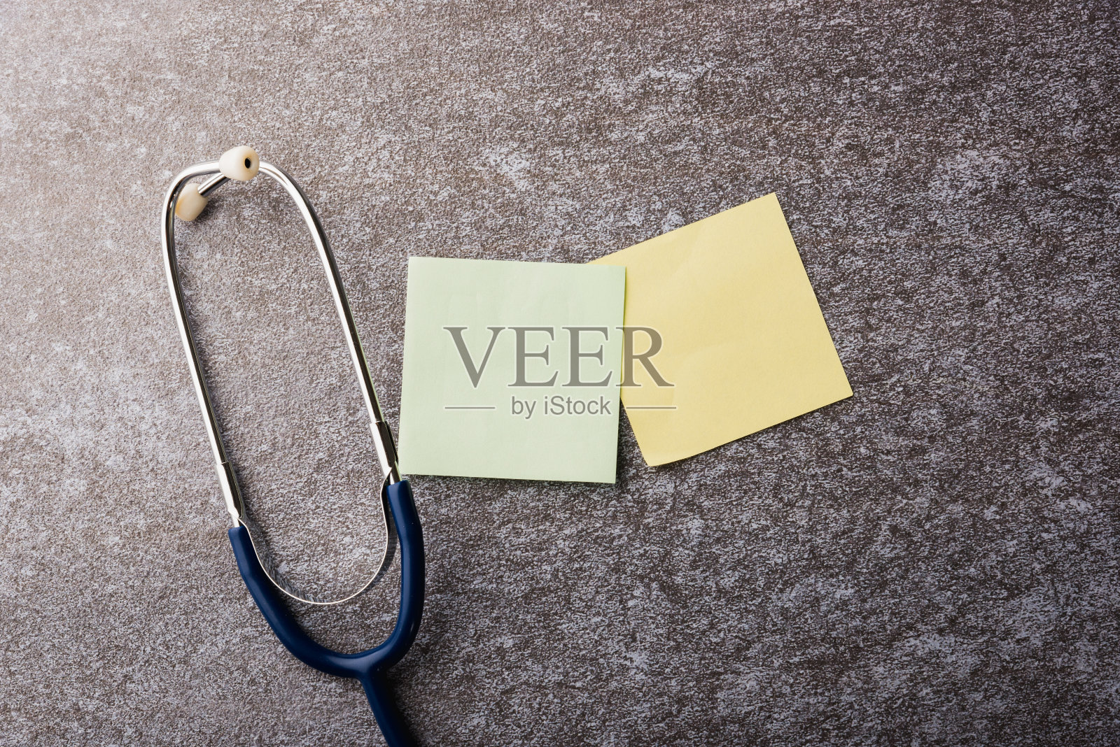 医生办公室的桌子桌上有空白纸贴便条和听诊器照片摄影图片