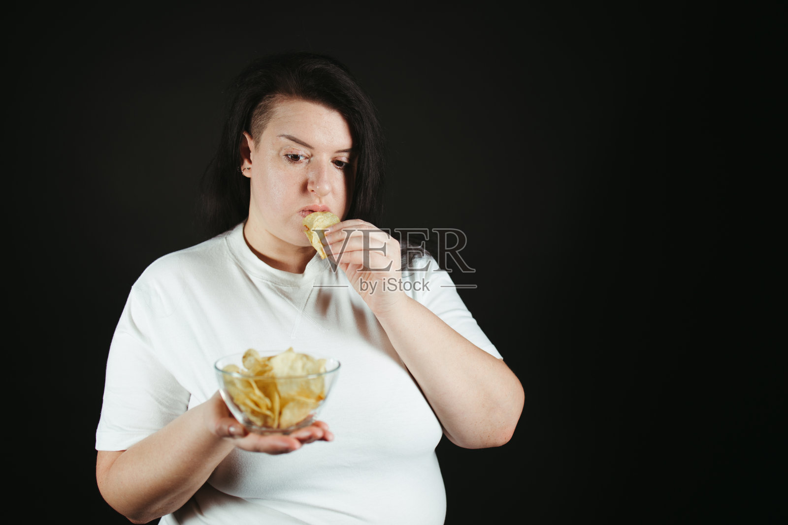 节食超重的女人吃薯片照片摄影图片