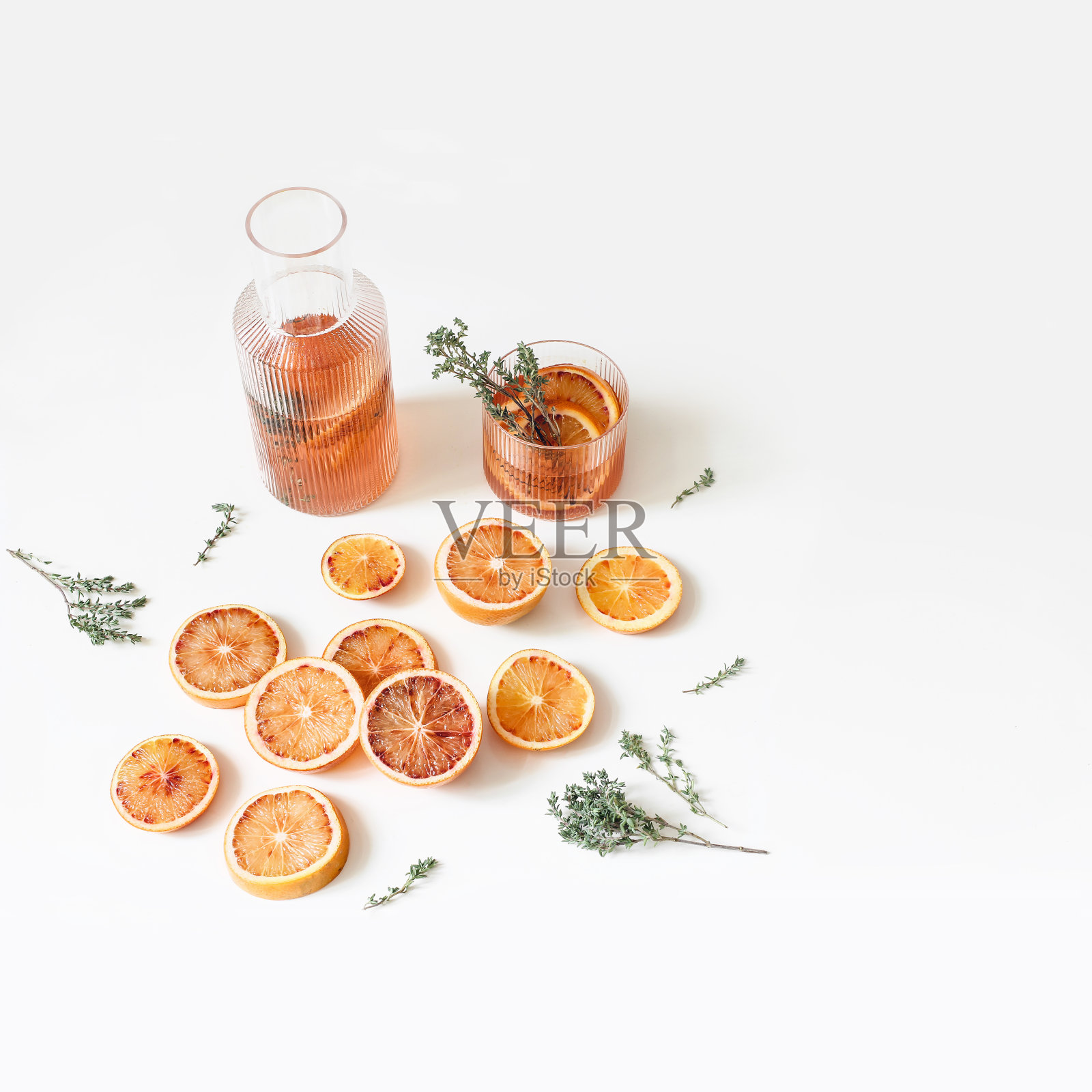 整个和切开的橘子和血橙水果。木砧板上放百里香,薄荷。白色背景。柠檬水饮料,鸡尾酒在玻璃水瓶。食品的概念。夏天网页横幅。照片摄影图片