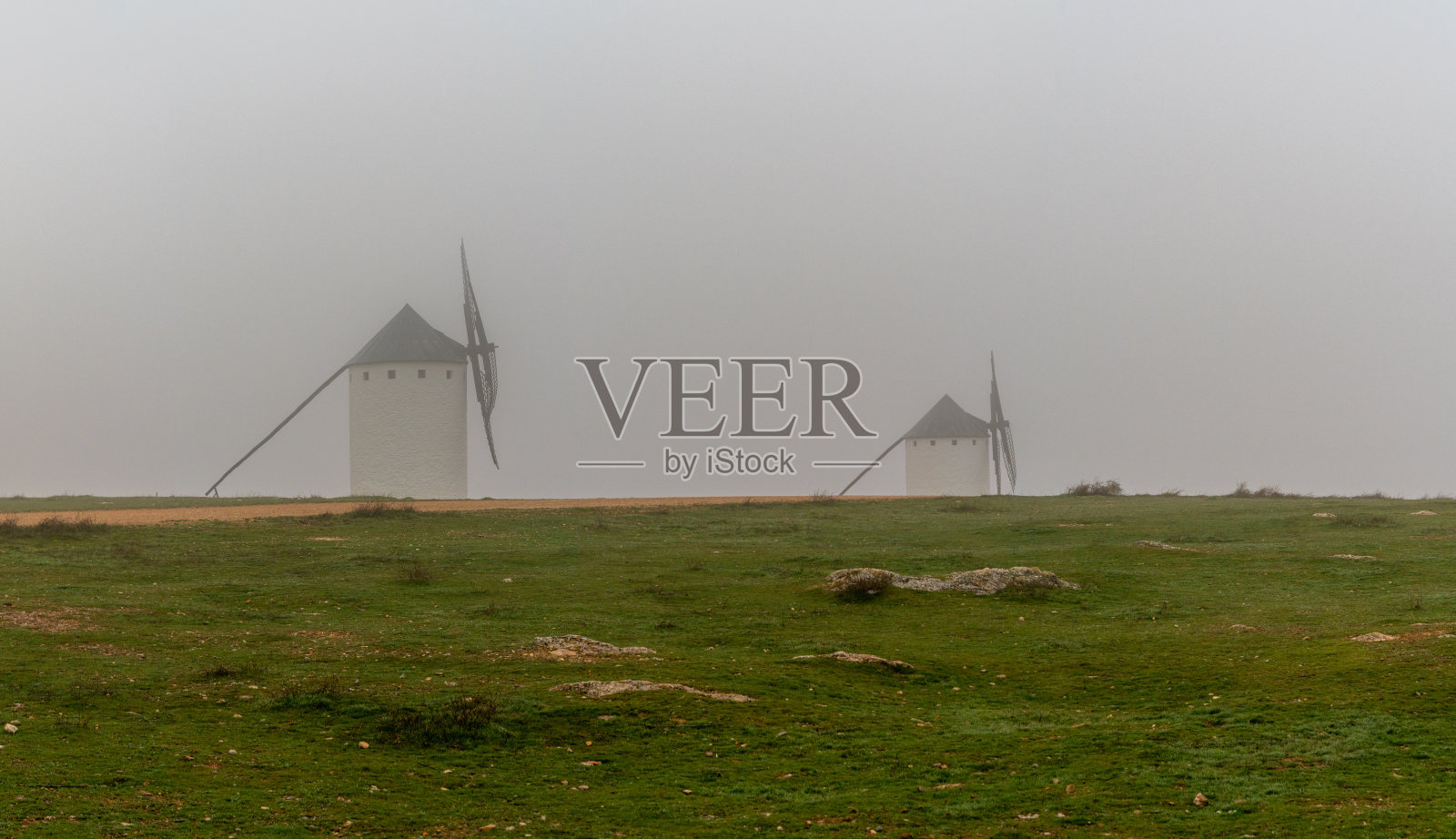 在一个雾蒙蒙的早晨,拉曼查的克里普塔纳广场的风车照片摄影图片