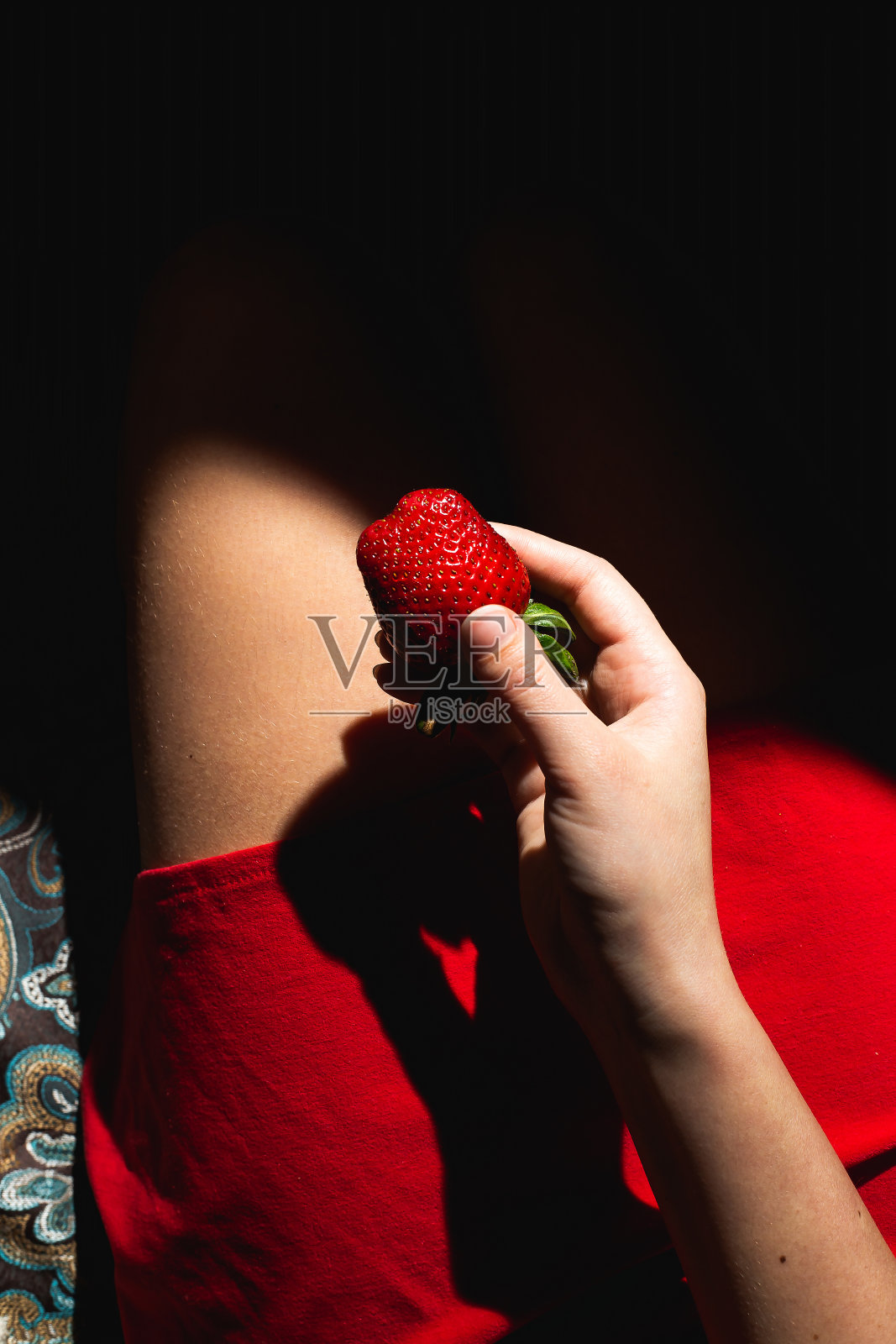 阳光下拿着多汁草莓的女孩照片摄影图片