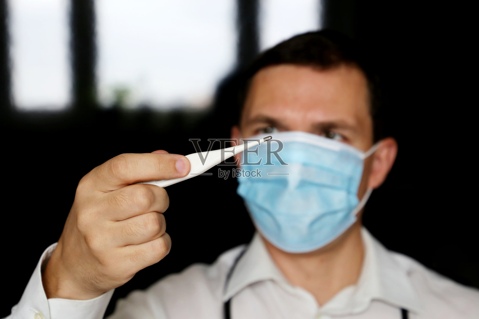 冠状病毒症状,戴医用口罩的人测量体温照片摄影图片