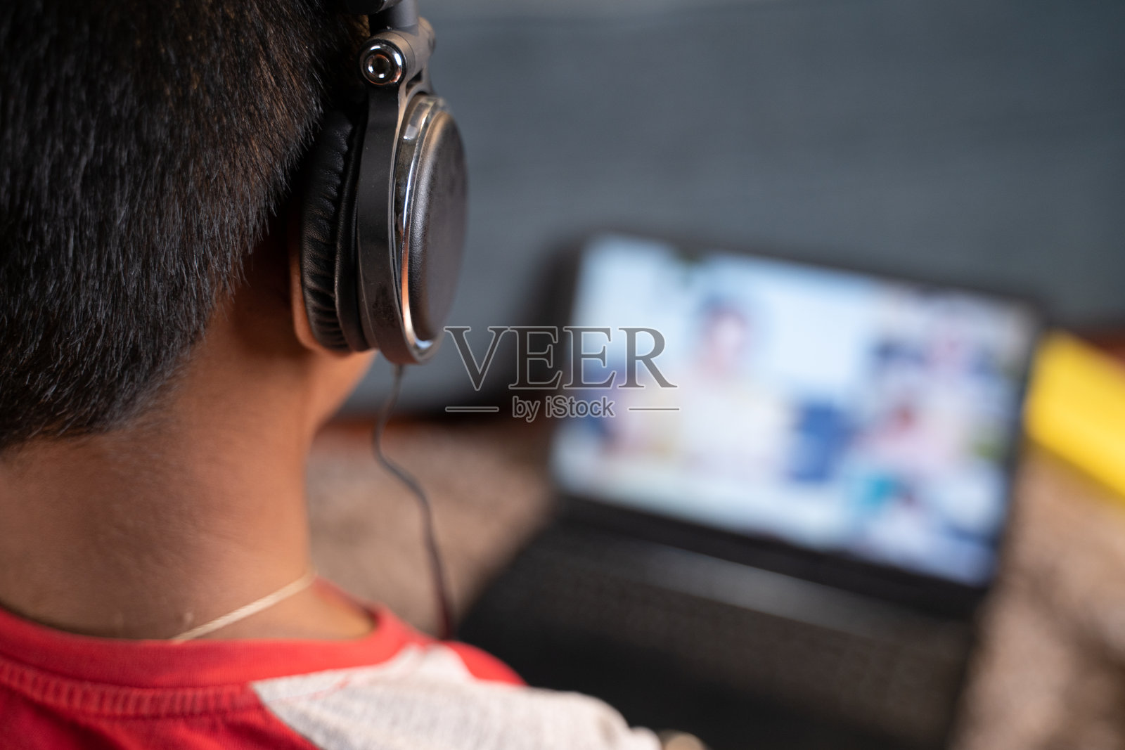 肩射少年用耳机听在线课程-在线虚拟教育的概念,新常态和家庭学校由于新冠肺炎大流行。照片摄影图片