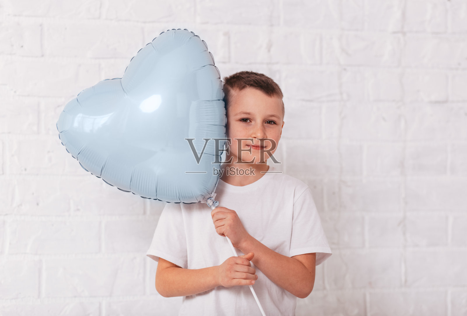 男孩拿着白色背景上的蓝色心形气球照片摄影图片