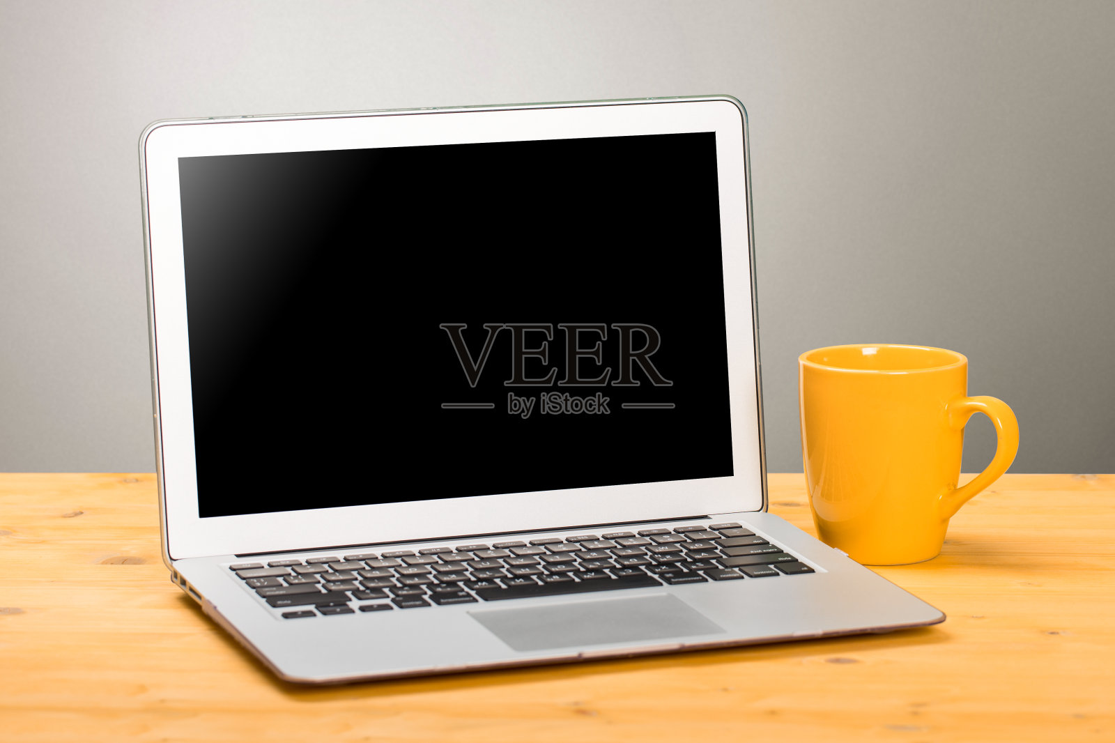 原型空白笔记本电脑屏幕和黄色咖啡在共同工作空间的木桌上。照片摄影图片